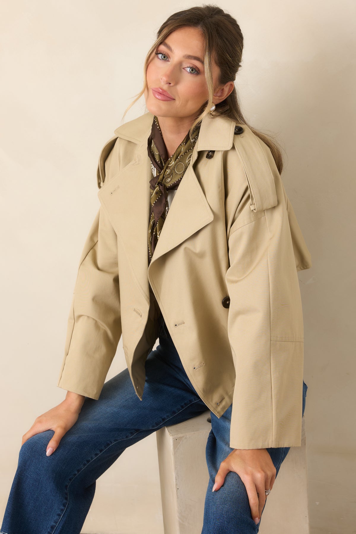 The elasticized waist adds definition to the relaxed cropped silhouette of this beige trench jacket.