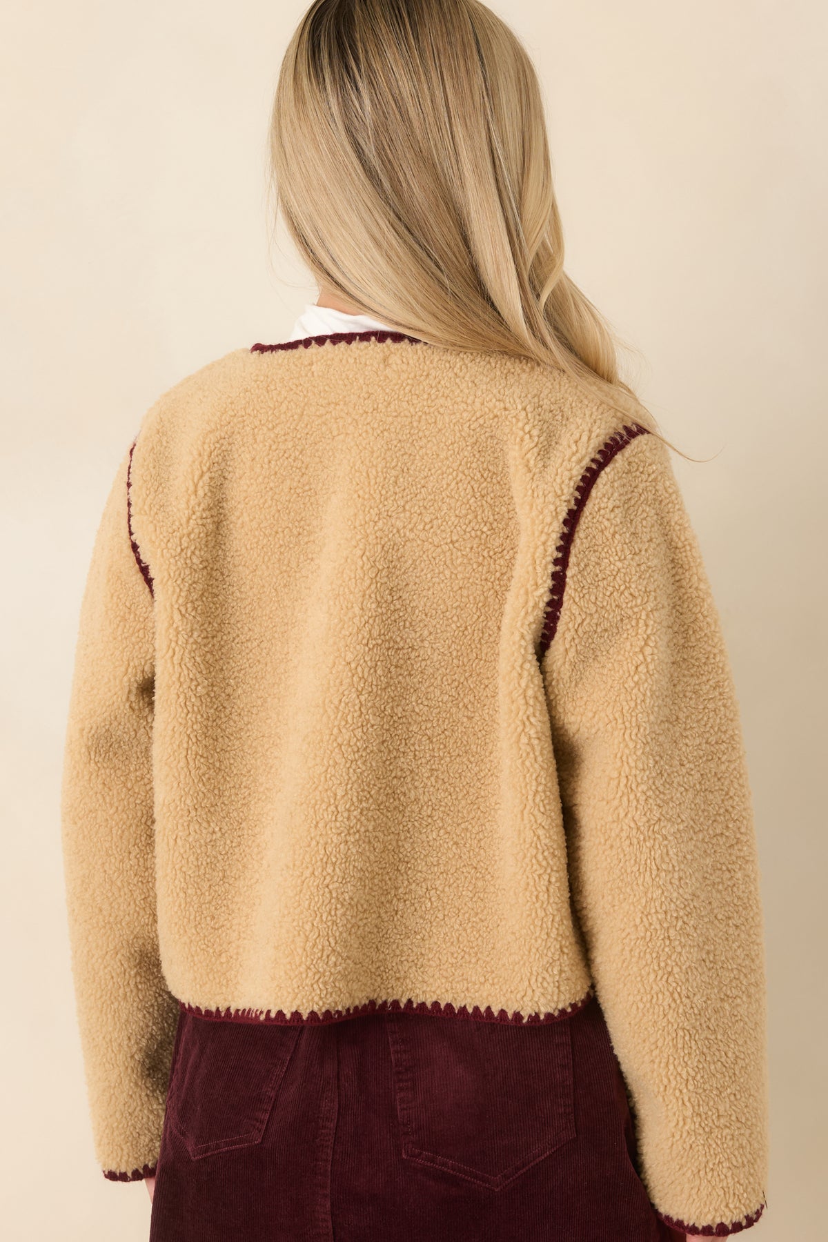 Beige faux sherpa jacket with a plush back, relaxed hip-length cut, and long sleeves.