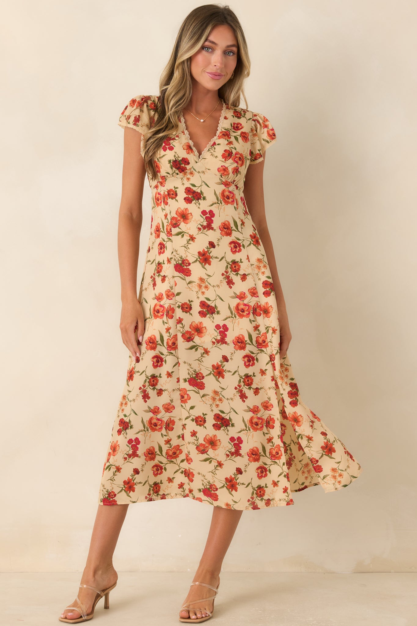 Beige floral midi dress featuring lace-trimmed surplice styling, flutter sleeves, a flattering empire silhouette, and a graceful drape.
