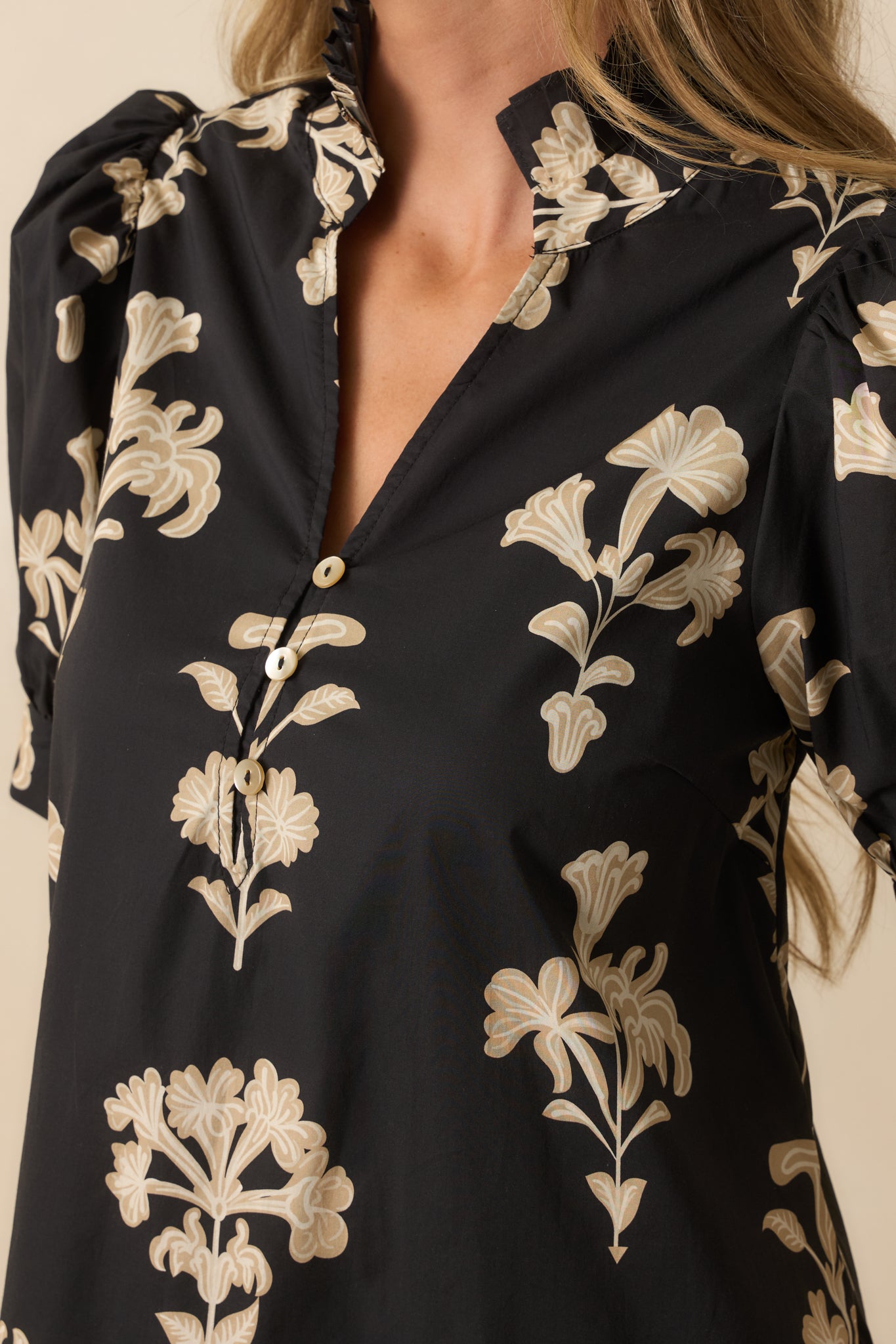 Zoomed-in view of the beige floral print, button-front detail, and textured puff sleeves.