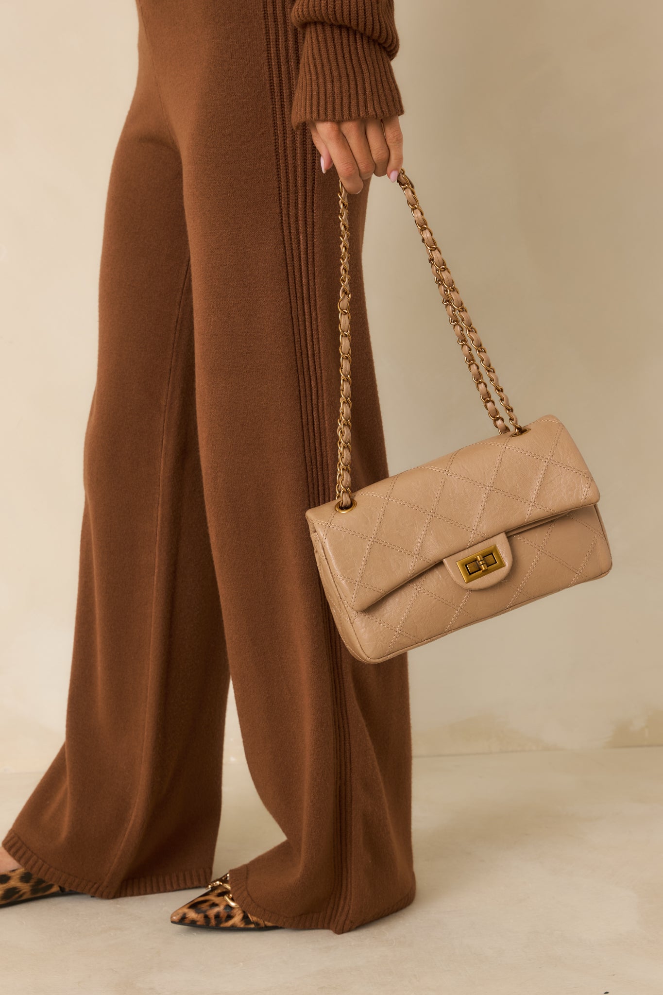 Beige handbag with a structured silhouette and diamond-quilted faux leather exterior.