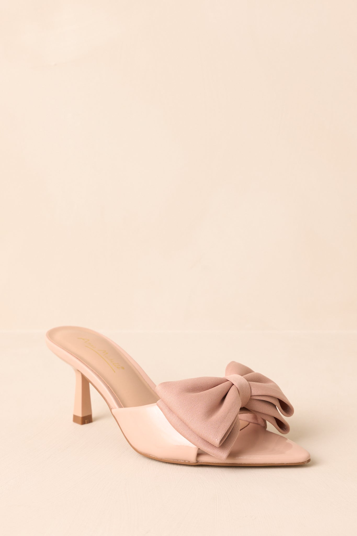 Beige kitten heel mule with pointed open-toe and bow strap.