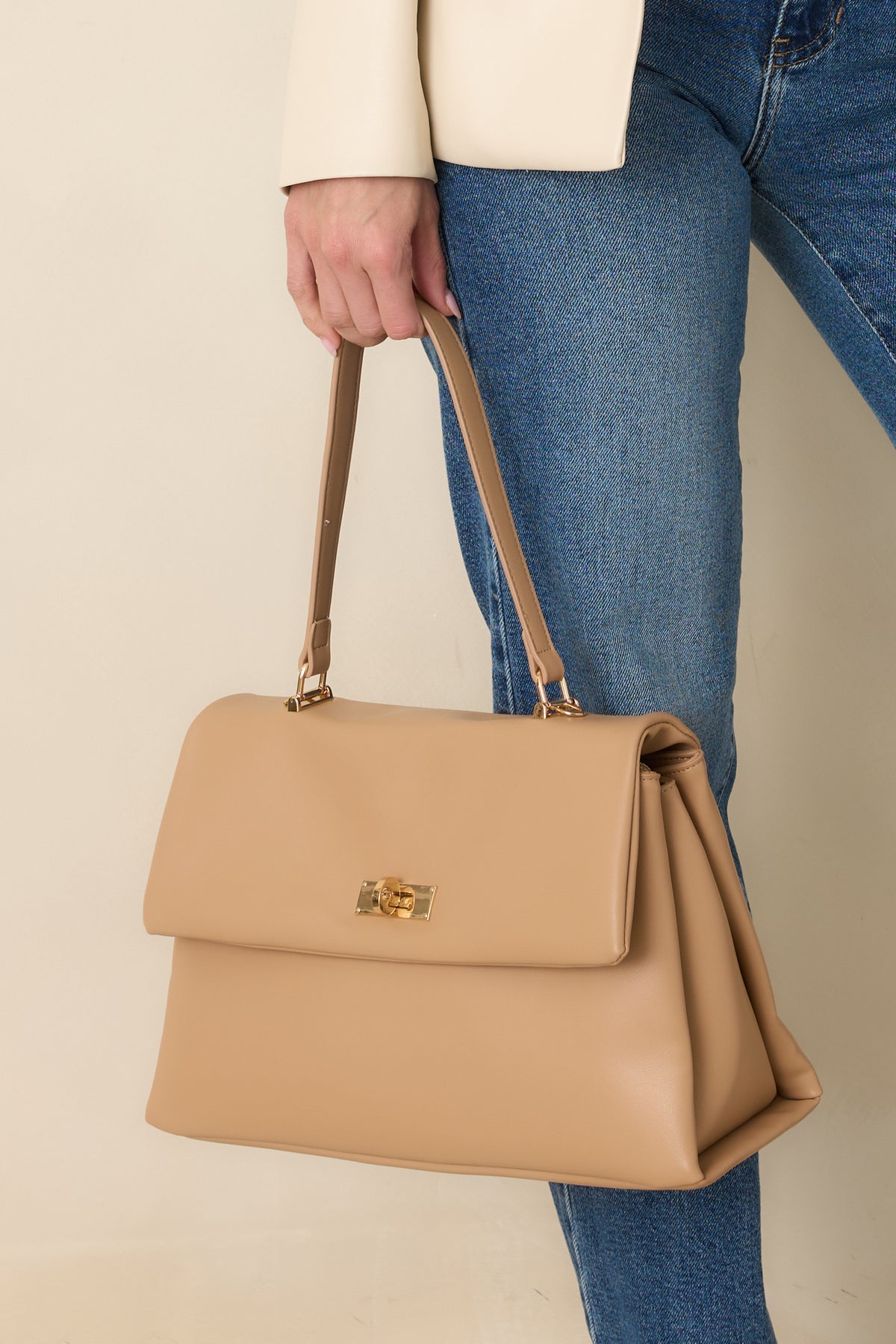 Structured beige leather handbag with gold-tone hardware, a flap top, and a twist-lock closure.