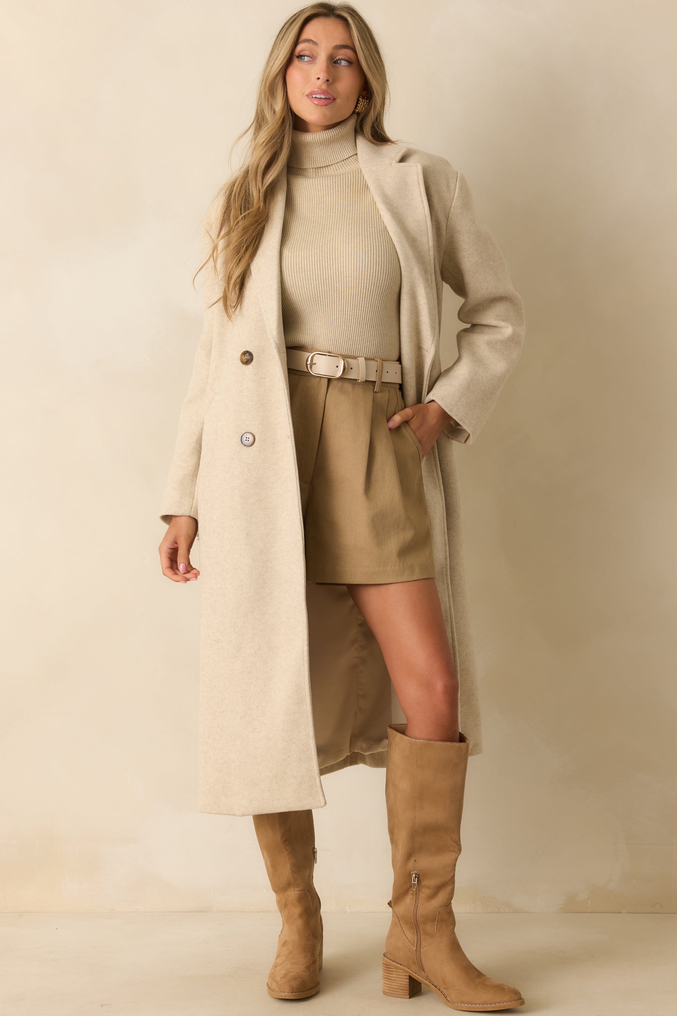 Light beige longline coat with double-breasted tortoise buttons, notched lapel, and functional pockets.
