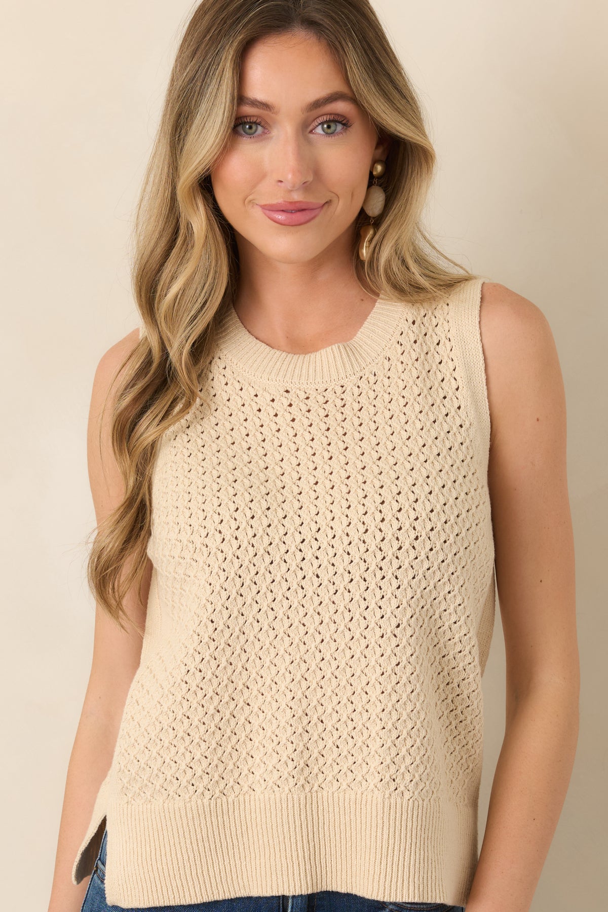 Beige open-knit top highlighting the round neckline and intricate airy stitching across the upper portion.