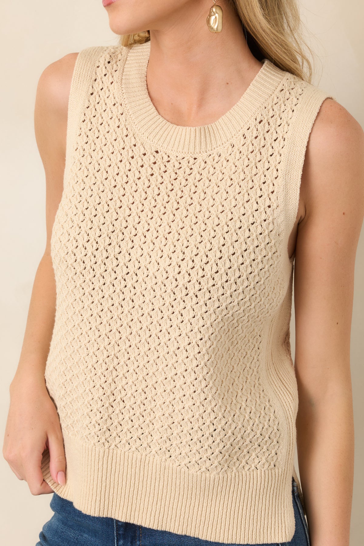 Close-up of the beige top revealing its intricate open-knit weave, soft texture, and defined ribbed edging.