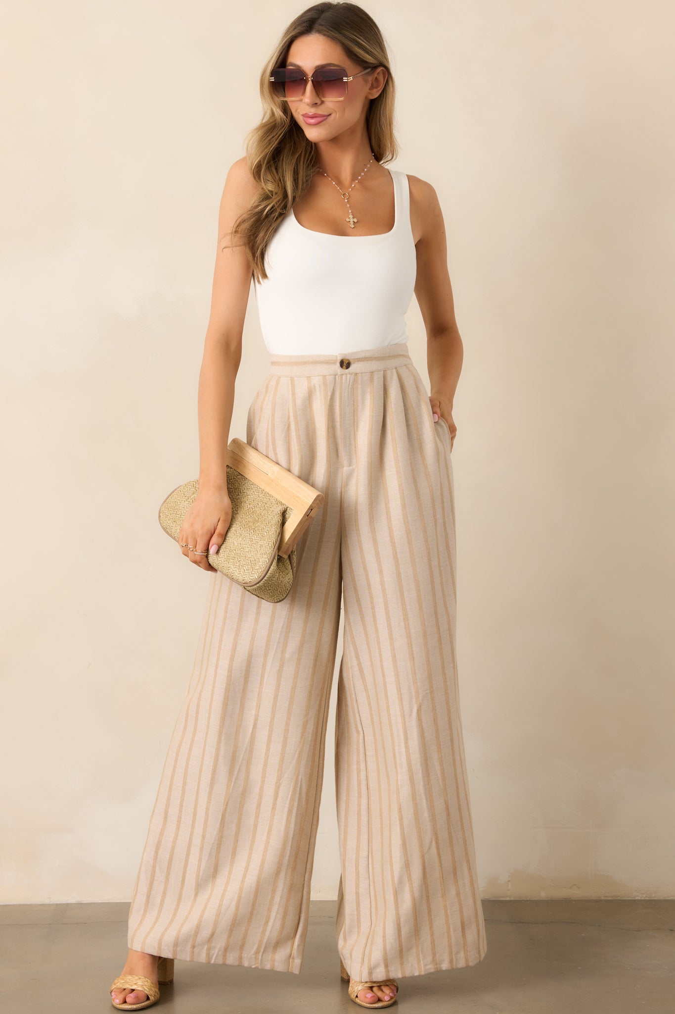 A pair of beige wide-leg pants featuring a zipper and tortoise shell button closure, adding a touch of sophistication.
