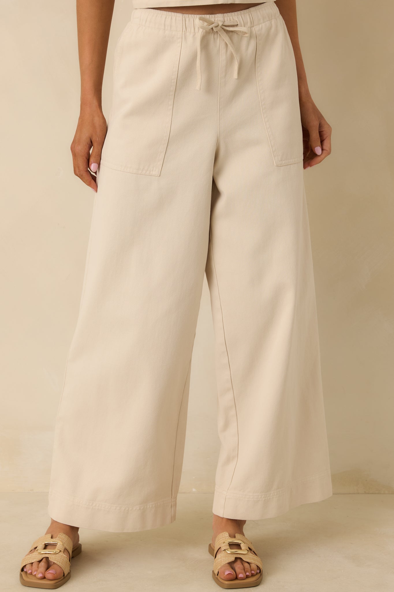 Front view of the beige pants highlighting the elastic waistband and adjustable drawstring tie.