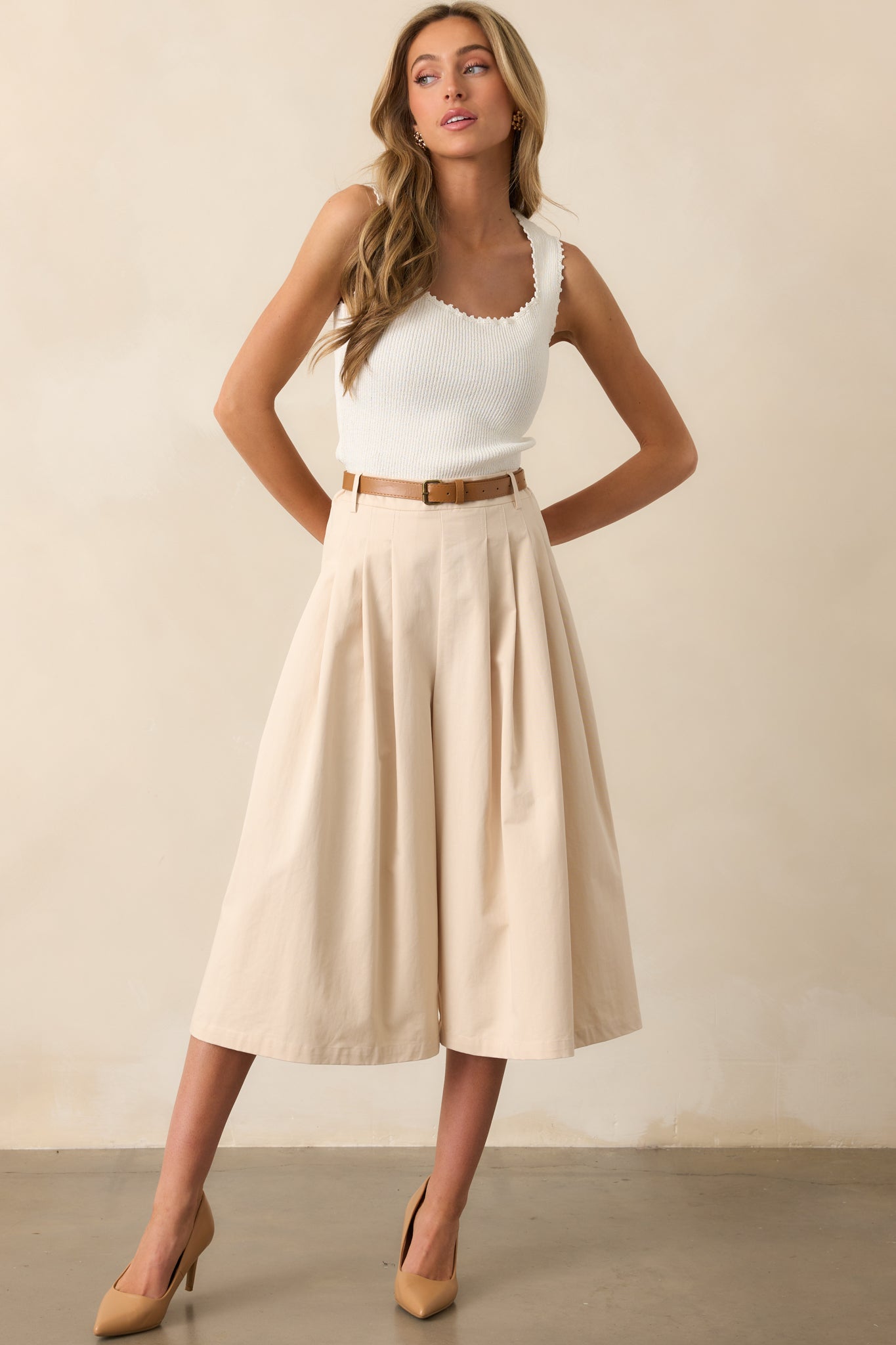 Statement-making beige pants with an ultra-wide leg, structured pleats, and a coordinating cognac brown belt.
