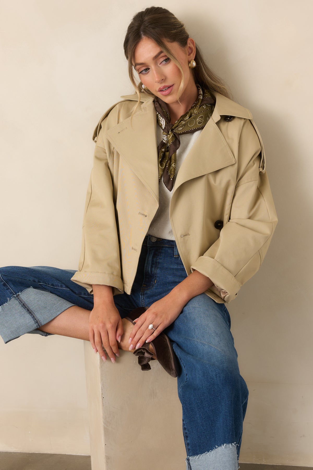 The cropped beige jacket features a relaxed fit with long sleeves and a clean double-breasted front.