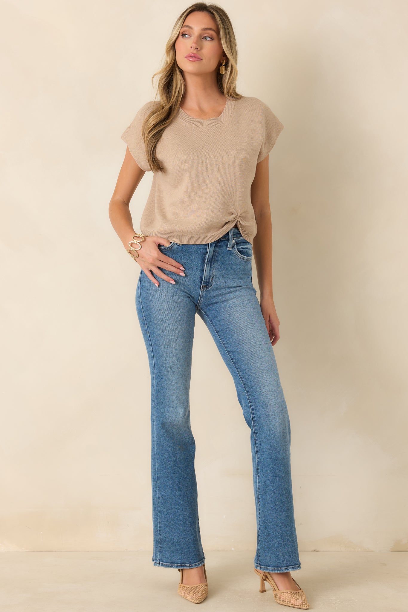 Front view of the beige lightweight knit sweater showcasing the relaxed silhouette, cap-style sleeves, ribbed crew neckline, and cinched front hem.