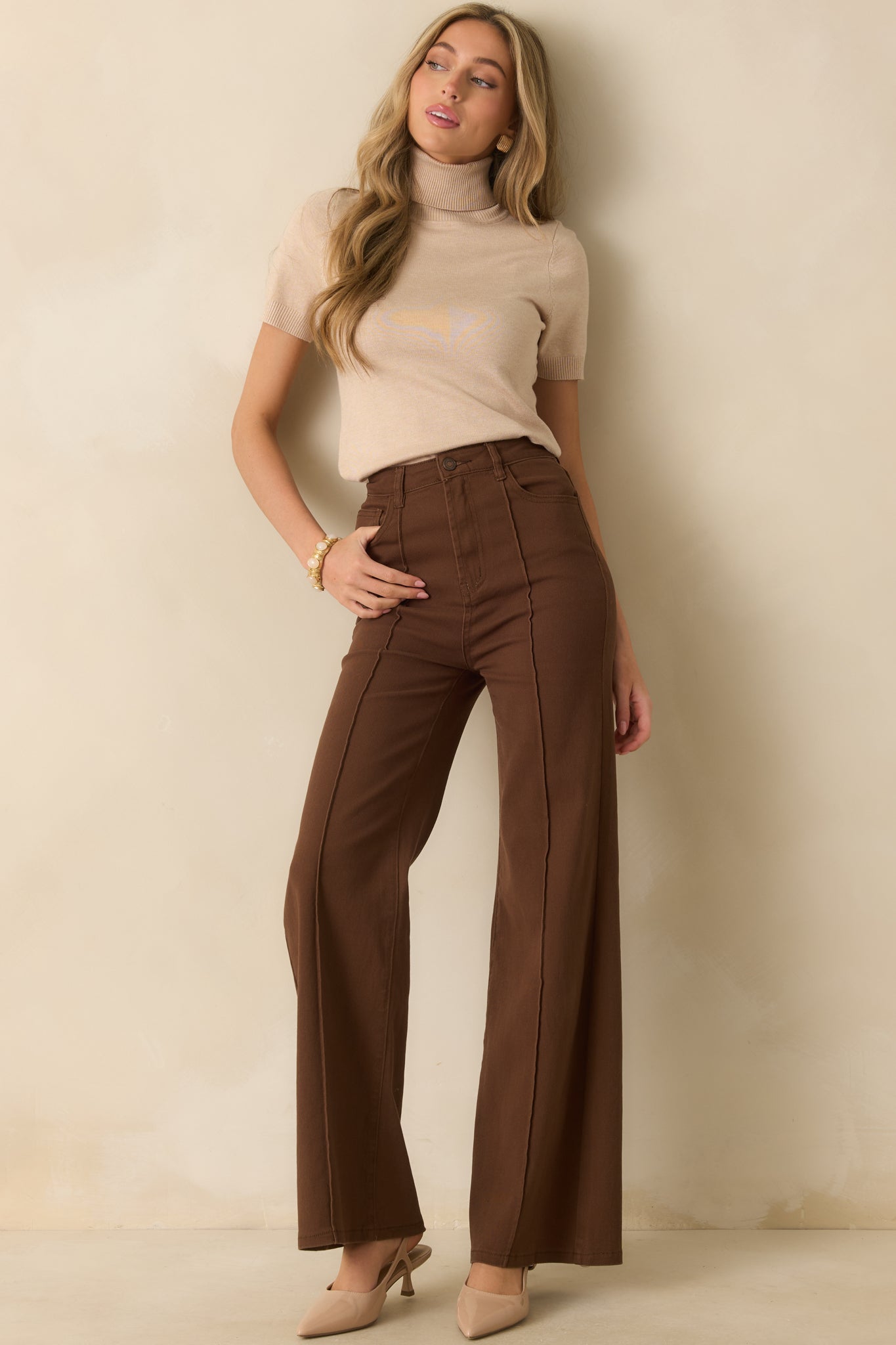 Beige ribbed knit sweater with rolled turtleneck, short sleeves, and slightly fitted silhouette.