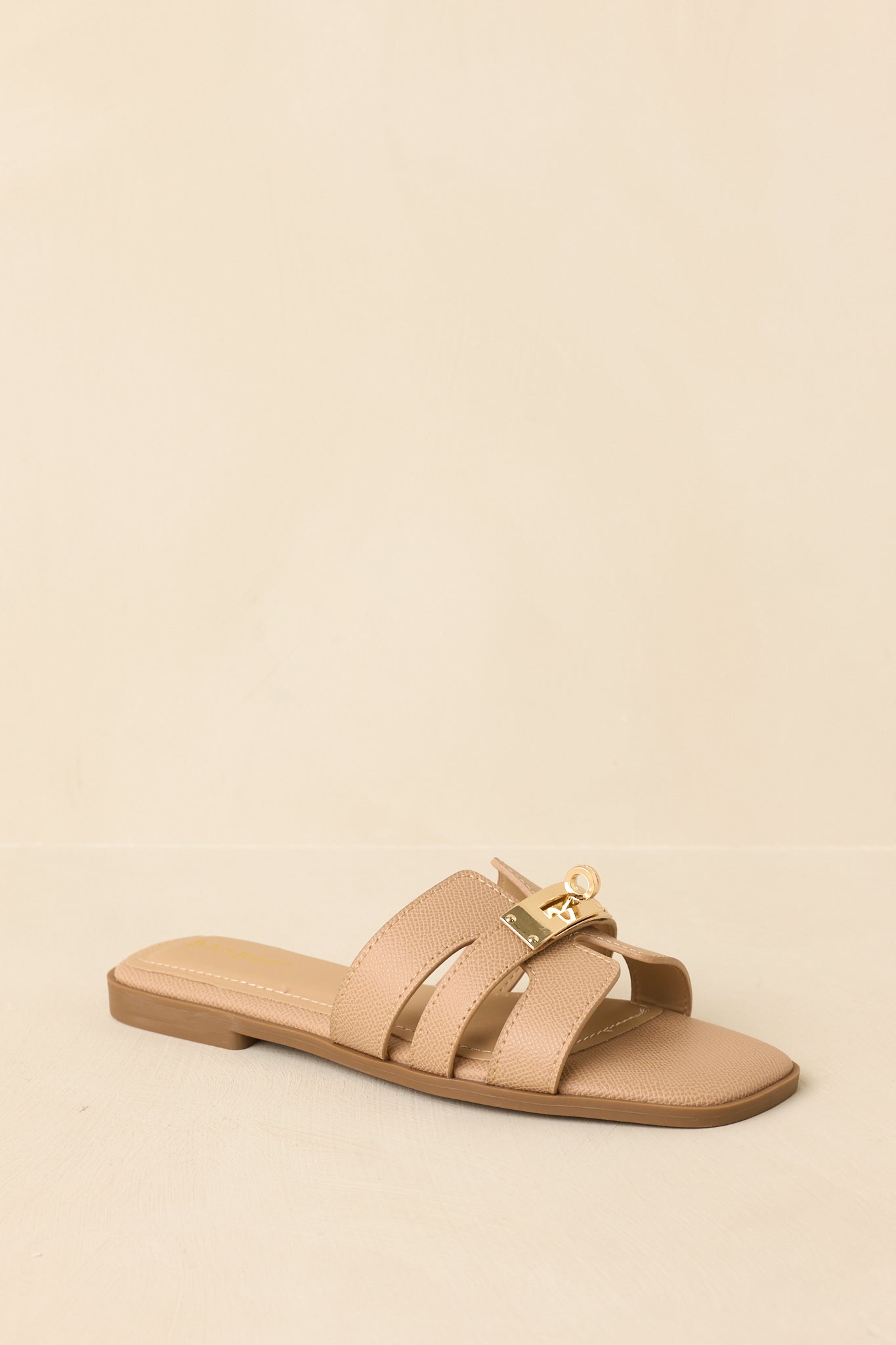 Front view of beige slide sandals displaying overlaid strap design and open toe.