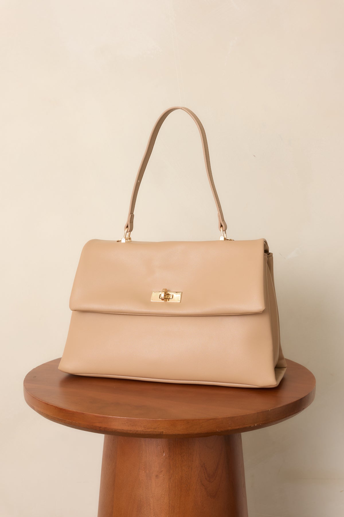 Beige handbag showcasing the flap top and clean structured leather construction.