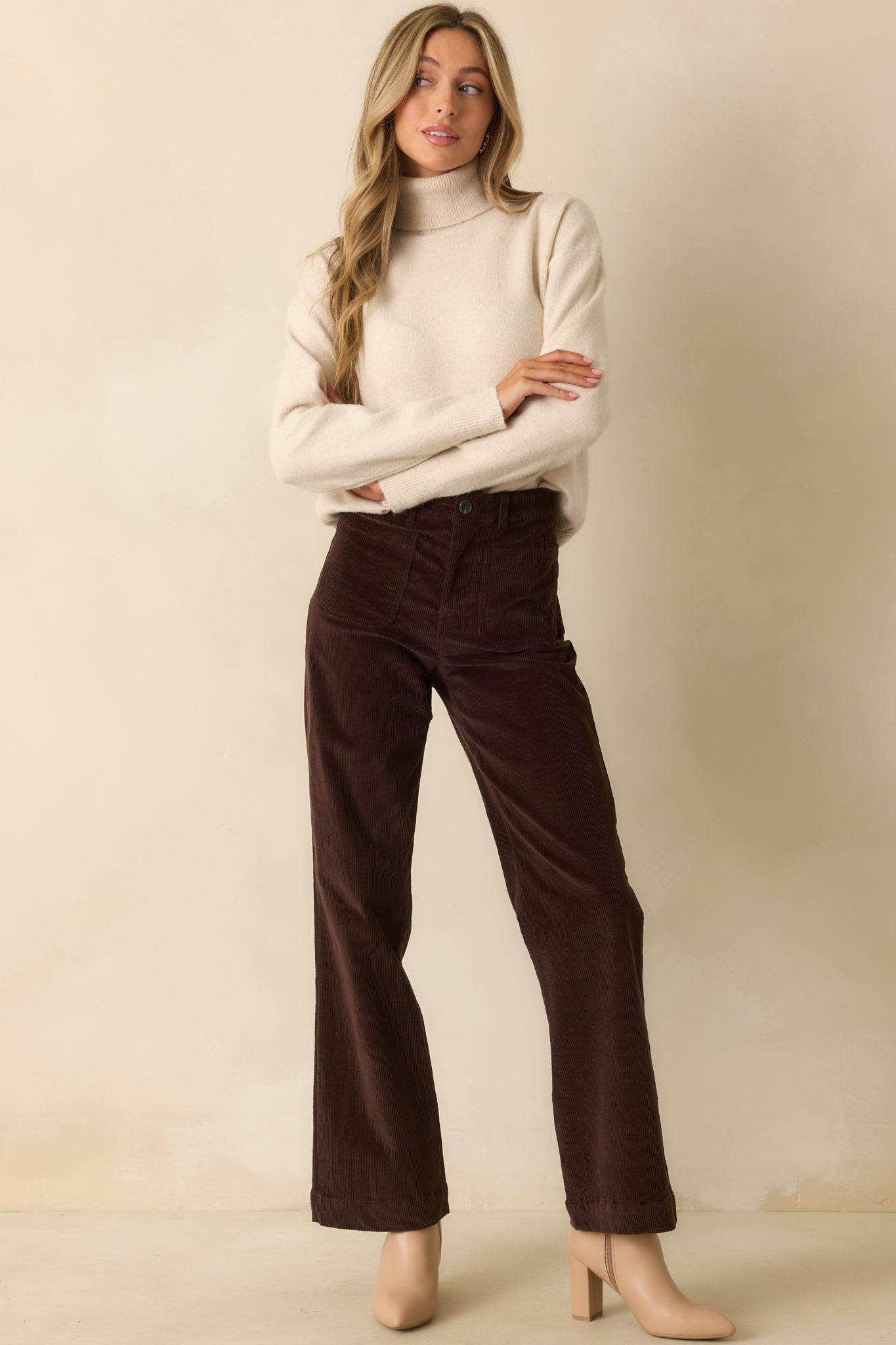 Light beige sweater with classic fold-over turtleneck, long sleeves, and relaxed silhouette.