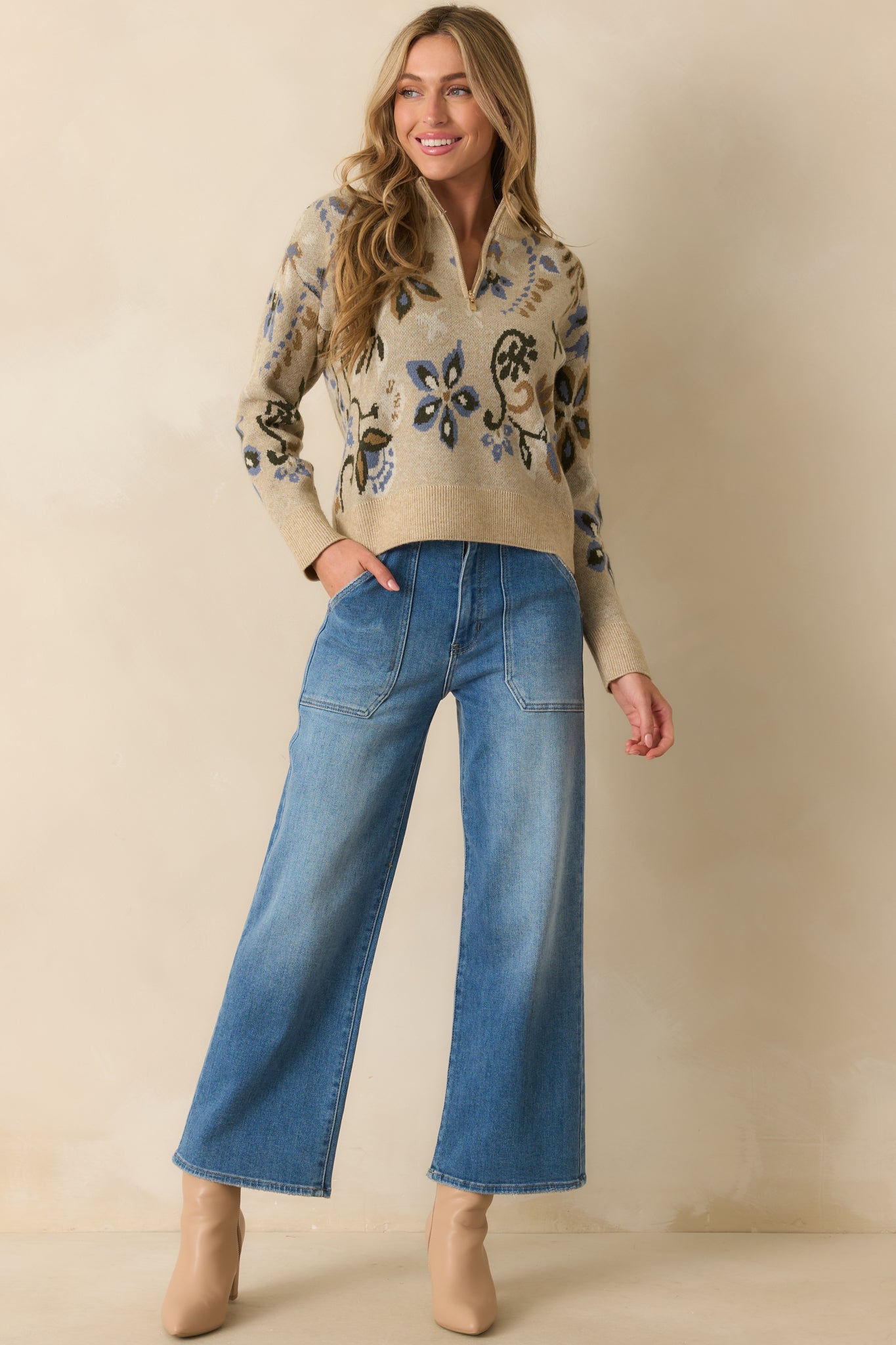 Cozy knit sweater in beige with a mock neck, blue floral pattern throughout, and relaxed fit.
