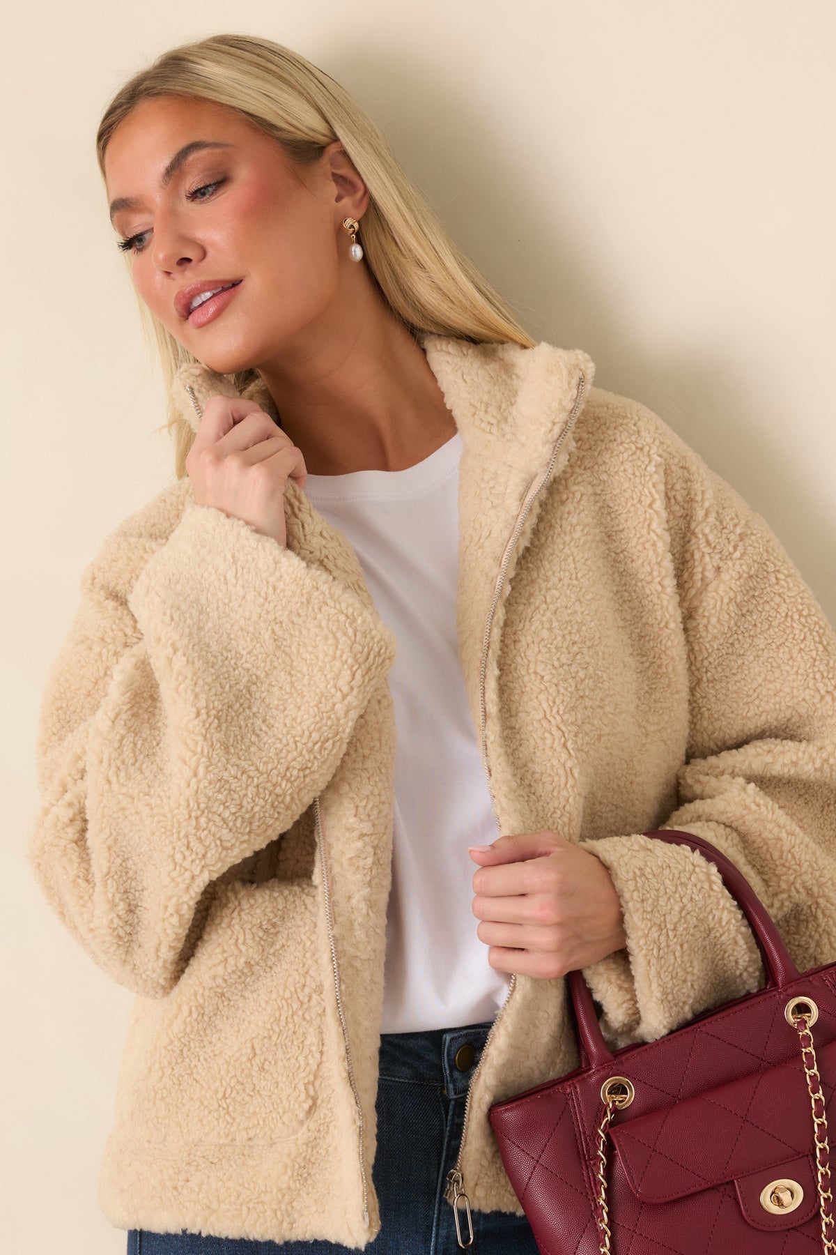 Beige teddy jacket highlighting the high stand collar and plush texture around the neckline.