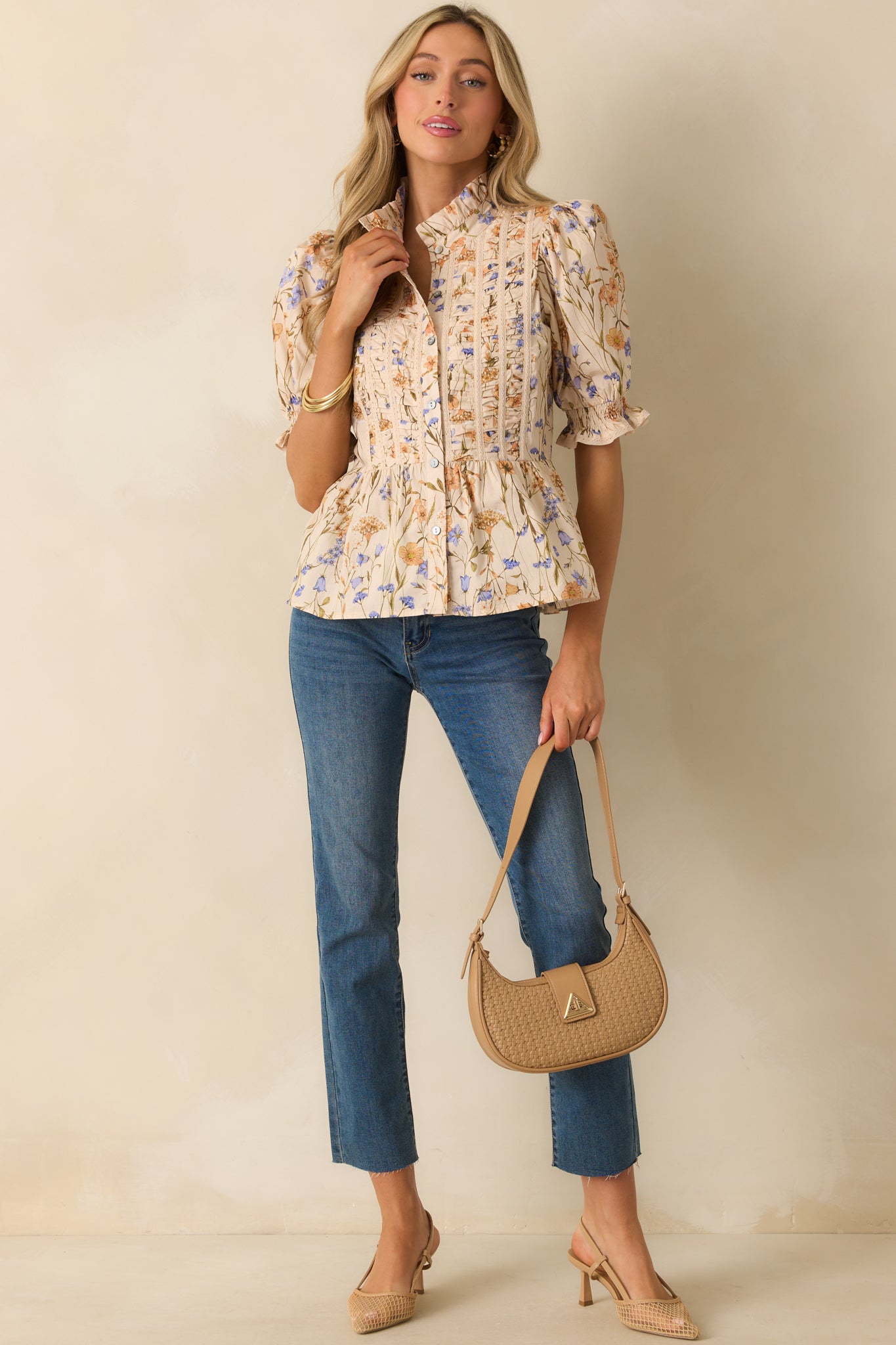 Beige top with multicolor floral print and high ruffle neckline.
