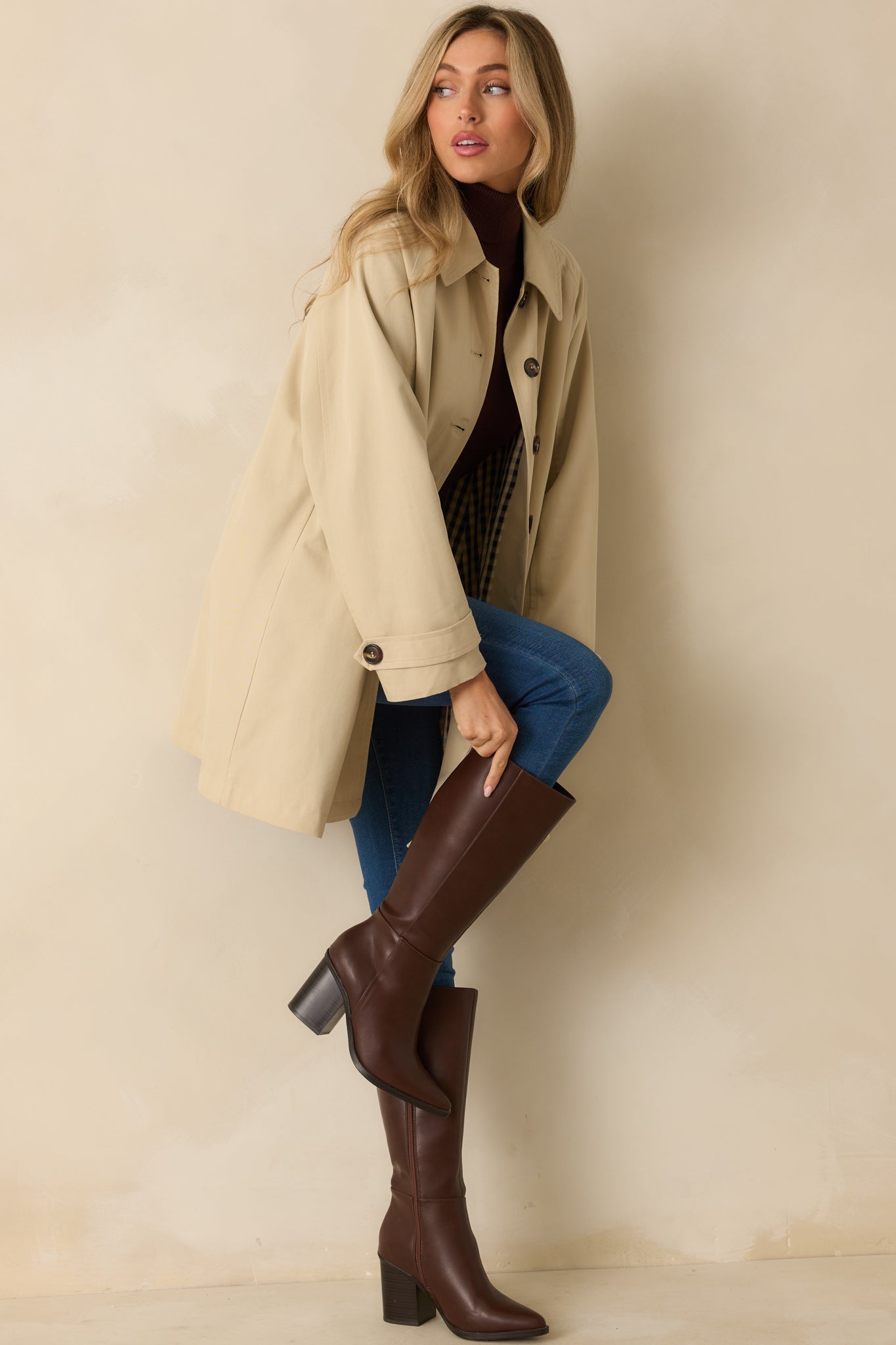 Beige trench jacket with collared neckline, long sleeves with button cuffs, and front button closure.