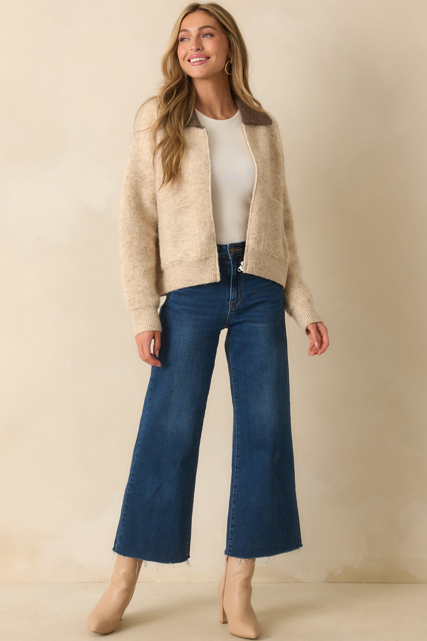 A front view of the beige zip-up jacket featuring a soft brushed knit fabric and a contrasting brown collar.