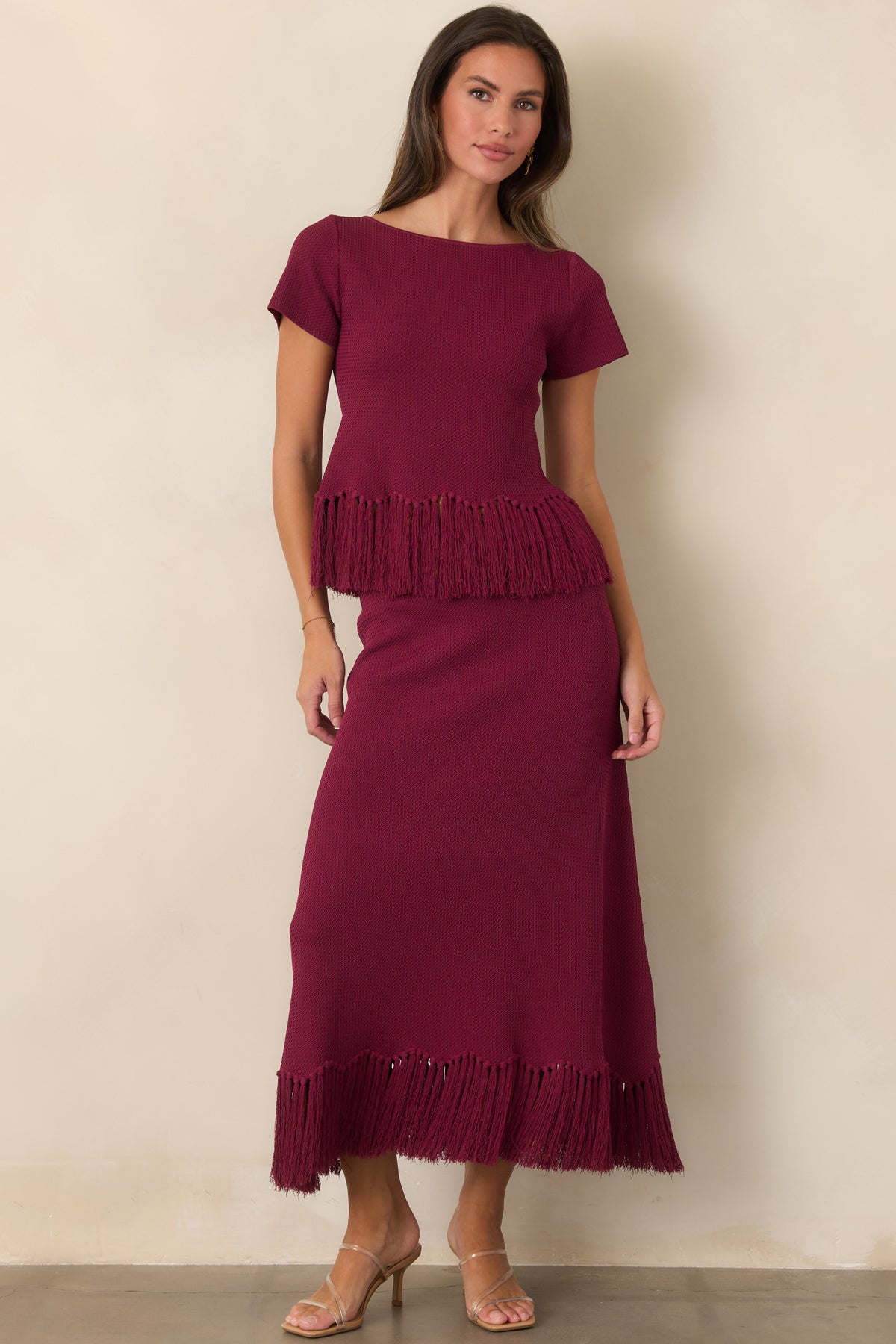Berry knit top with a gently shaped silhouette and swishy fringe along the hem.
