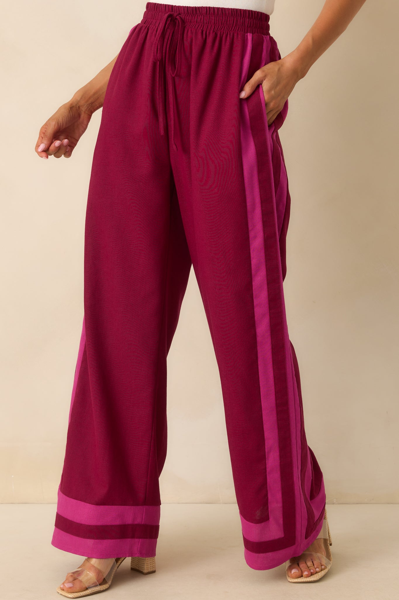Zoomed-in image of the berry pants focusing on the pink contrast trim along the leg seam and near the pocket opening.