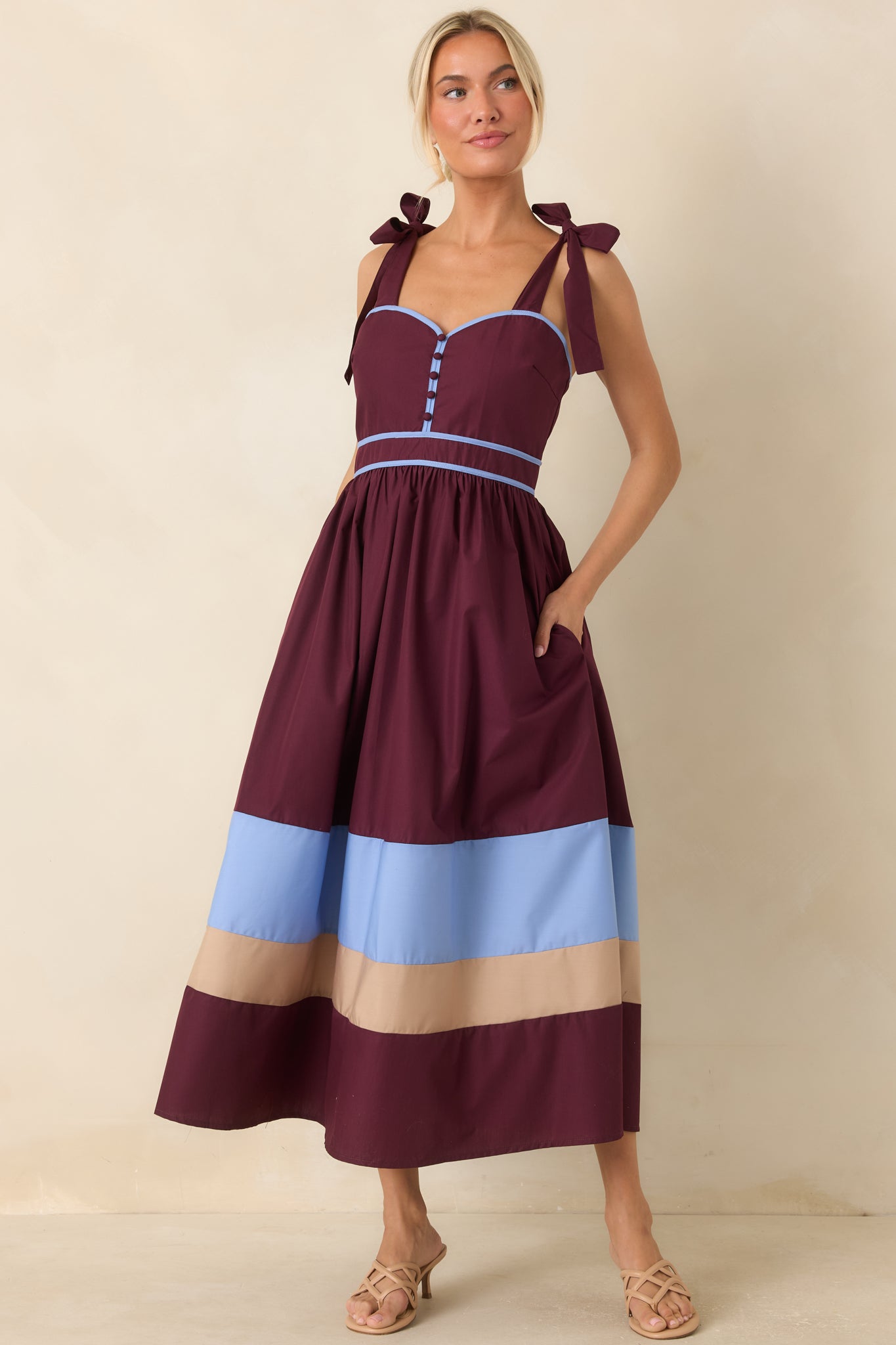 Berry and powder blue midi dress featuring a structured sweetheart neckline, gathered skirt, contrast trim, and bold color-blocked hem.