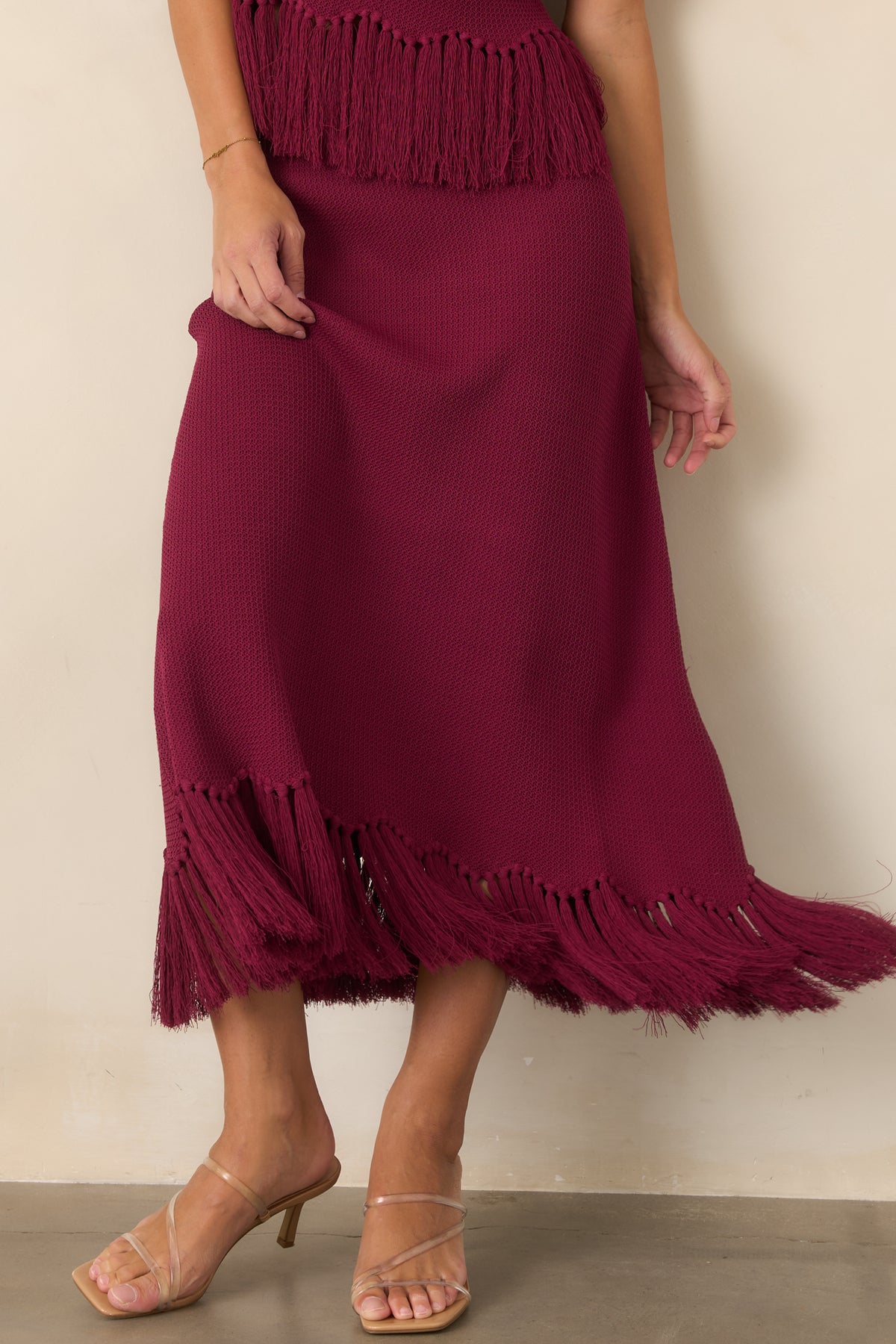 Berry textured knit skirt highlighting the fitted hip area and gradual widening toward the hem.