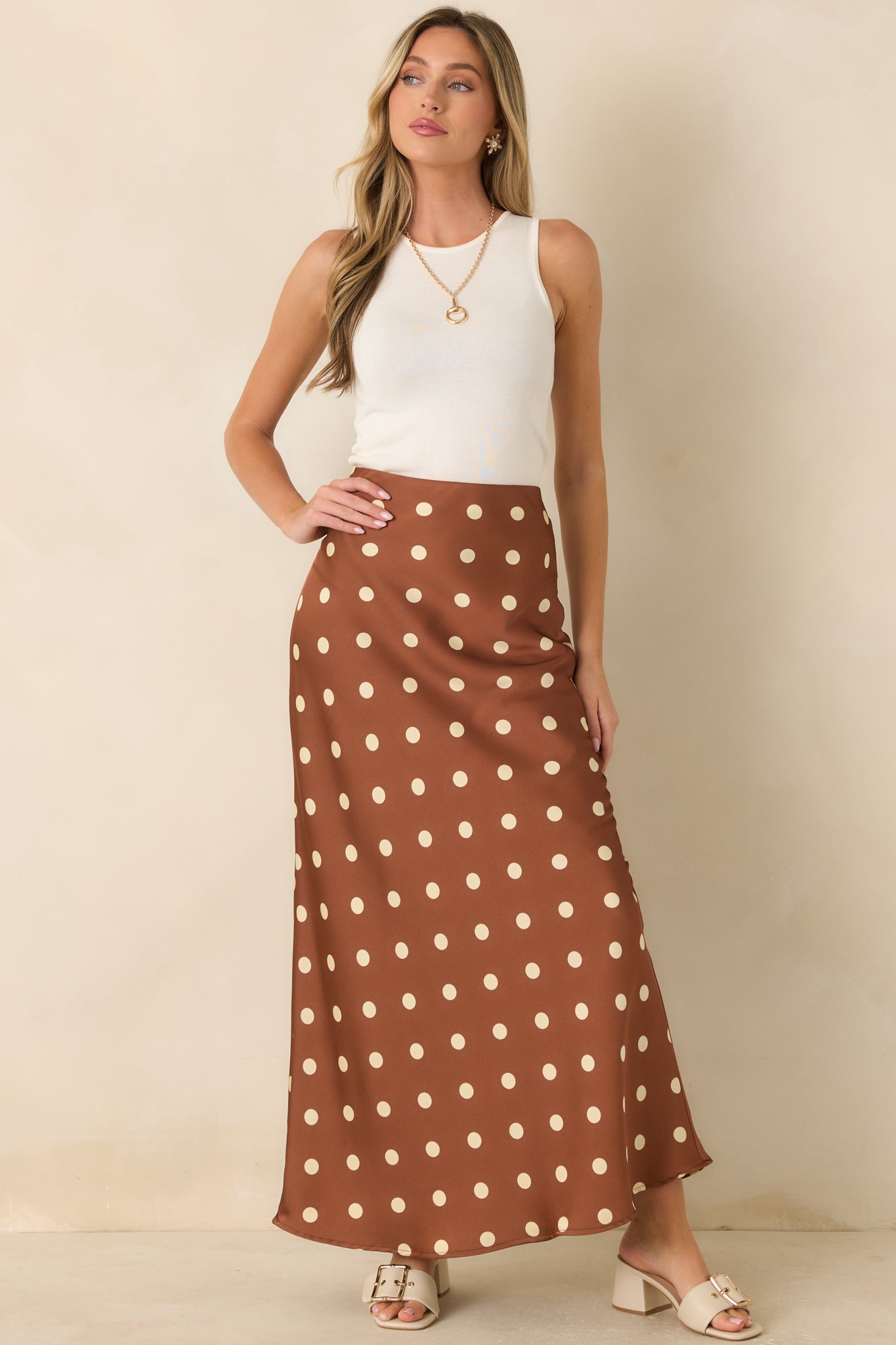 Bias-cut brown maxi skirt showcasing a fluid silhouette, soft ivory dots, and timeless satin finish.