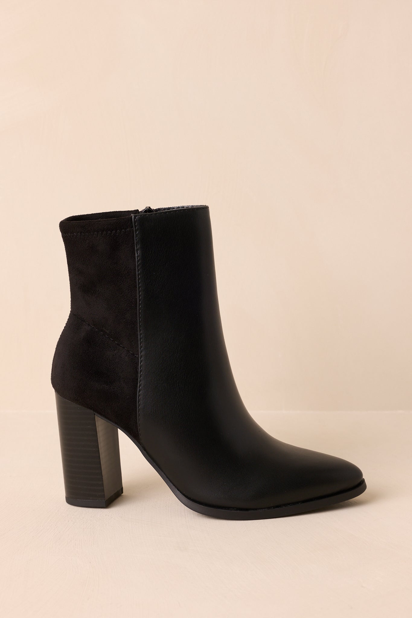 Black ankle boots with a sleek faux leather finish, soft suede back panel, side zipper closure, and comfortable block heel.