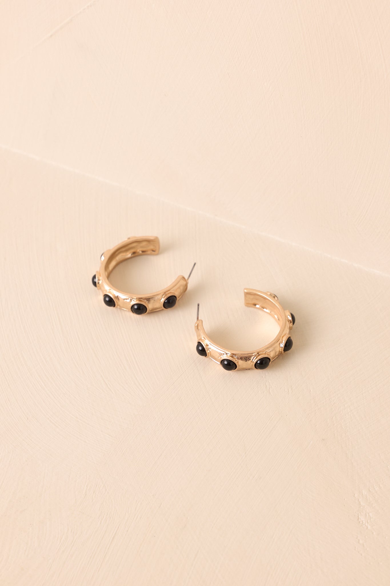 Black bezel set stones along gold textured open hoop earring.