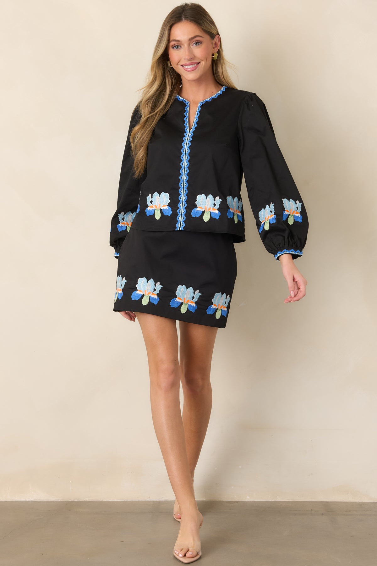 Black blouse featuring blue iris embroidery with colorful geometric accents.