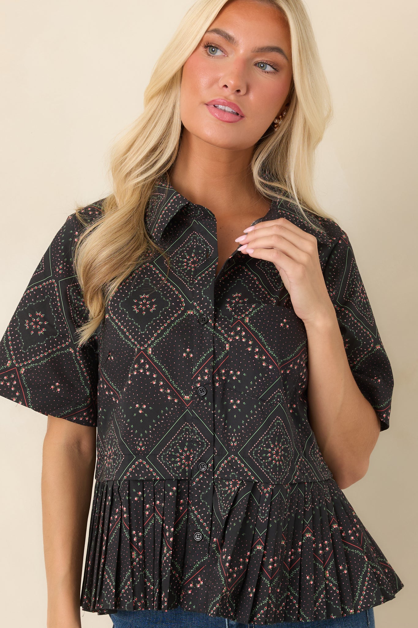 Collared neckline and functional button-front closure framed by a black cotton fabric with coral and green floral motifs in a geometric scarf-inspired print.