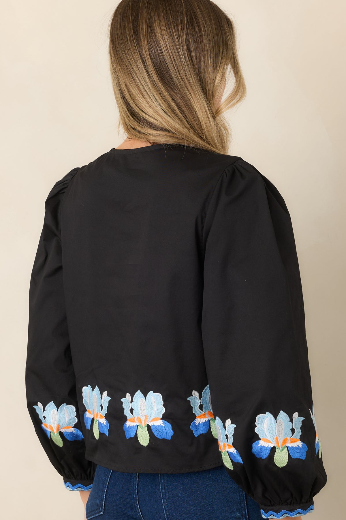 Rear of the black blouse showing its slightly cropped silhouette and puff sleeves.