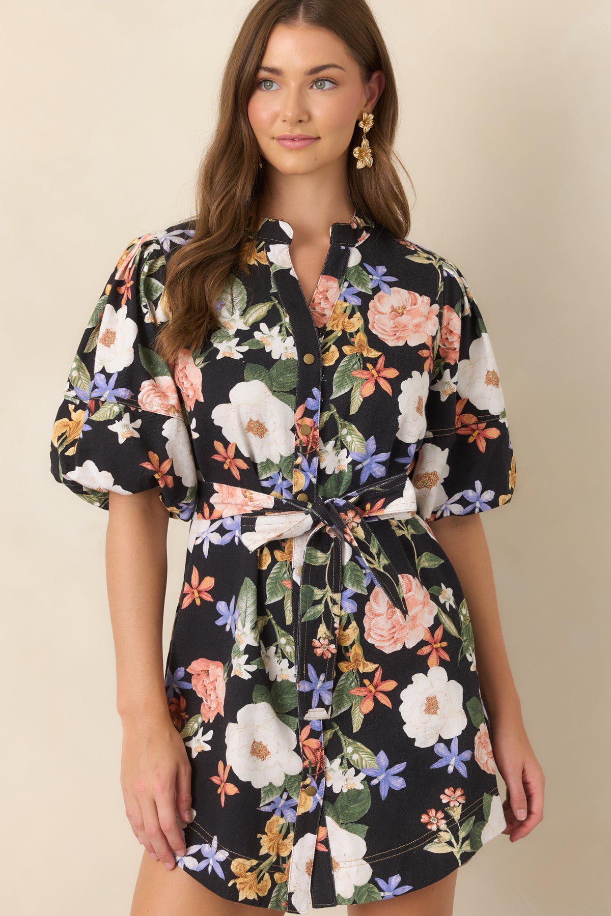 Colorful floral pattern decorates the black mini dress, accented by voluminous elbow-length sleeves and a relaxed shape.