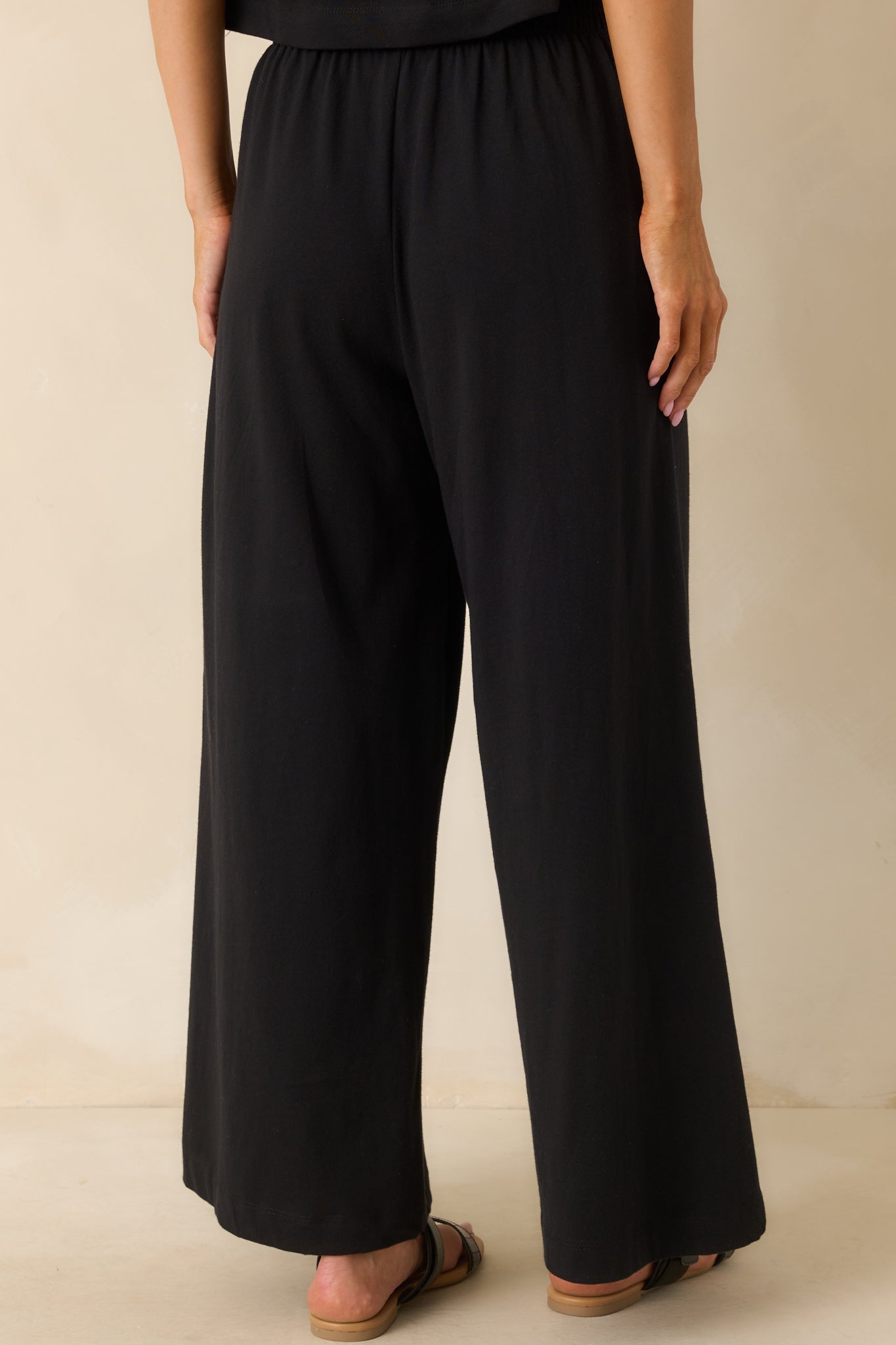 A back view of the black pants featuring the high waist and relaxed fit continuing through the wide legs.