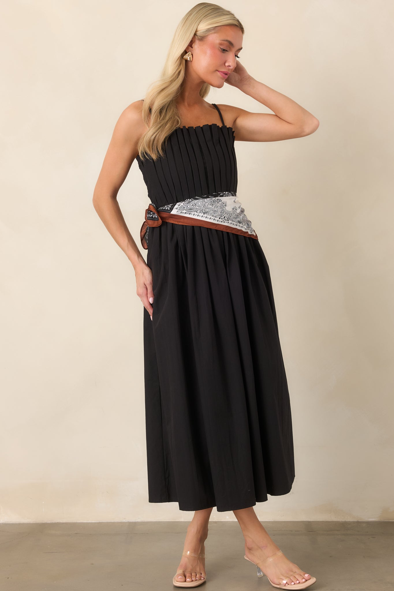 Sleek black cotton dress with a structured square neckline, slender adjustable straps, defined waist, and softly flowing midi skirt.
