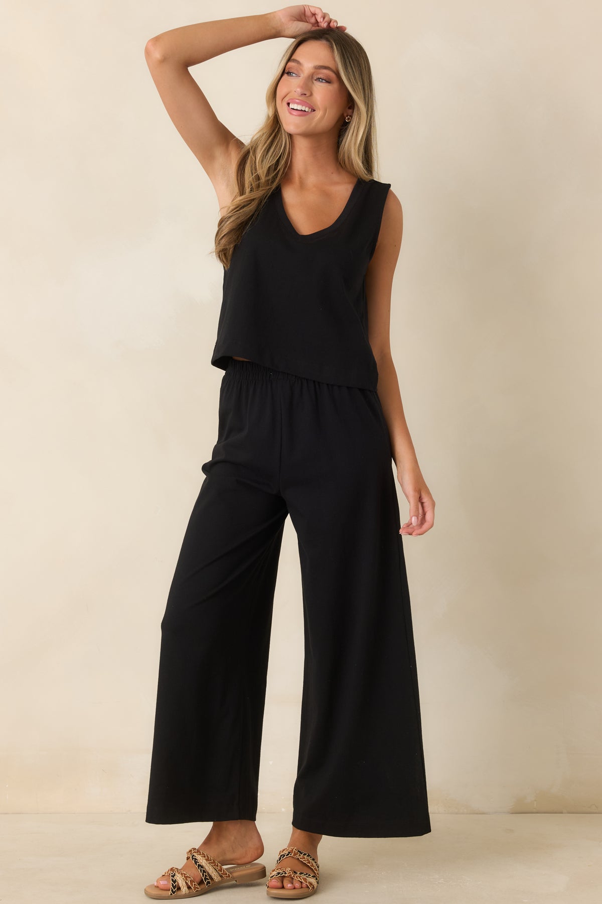 Black cotton tank top featuring a v-neckline, sleeveless design, relaxed fit, and cropped length.