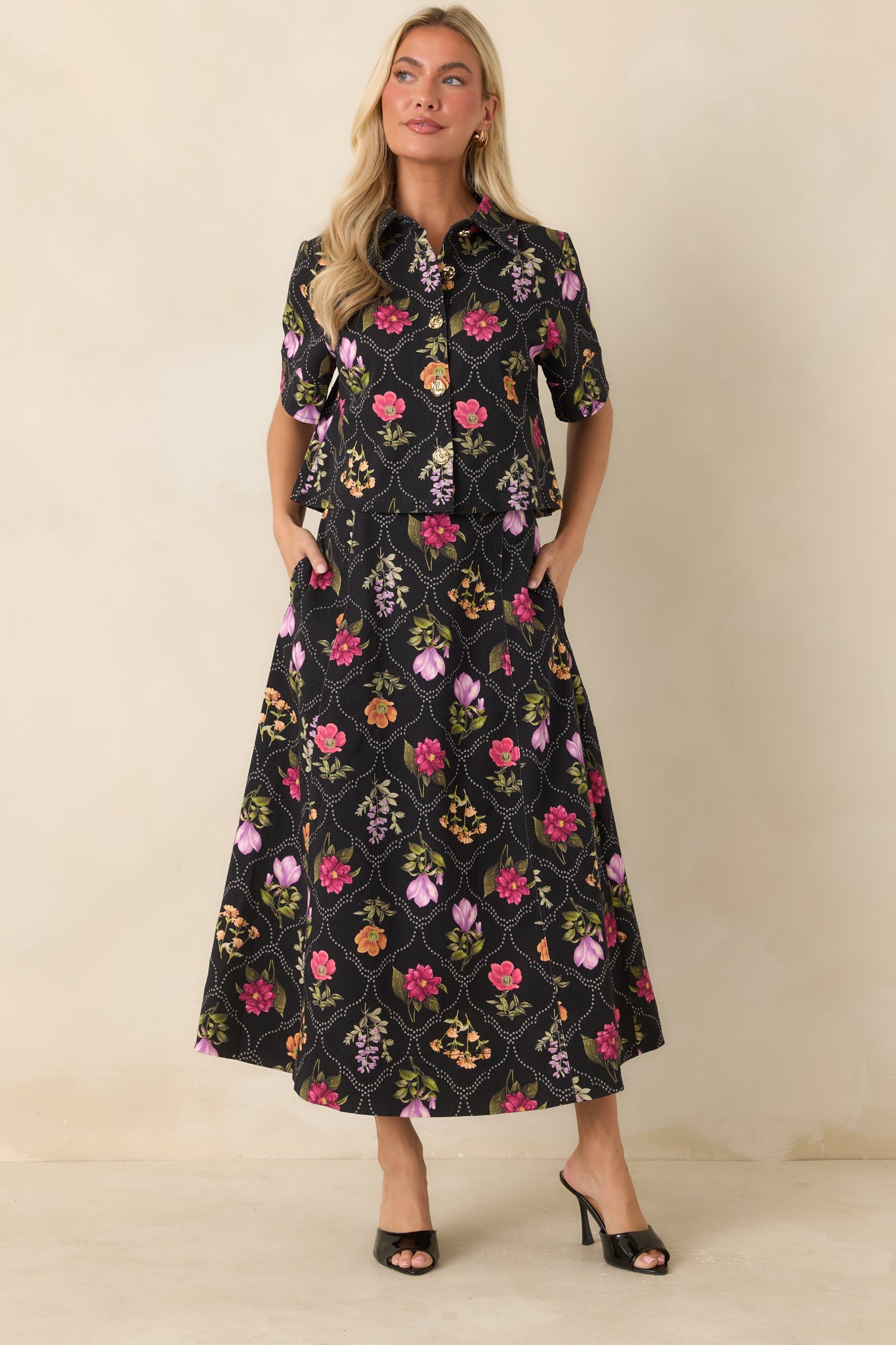 Black cropped blouse showcasing colorful florals, structured fabric, and decorative gold-tone button detailing.