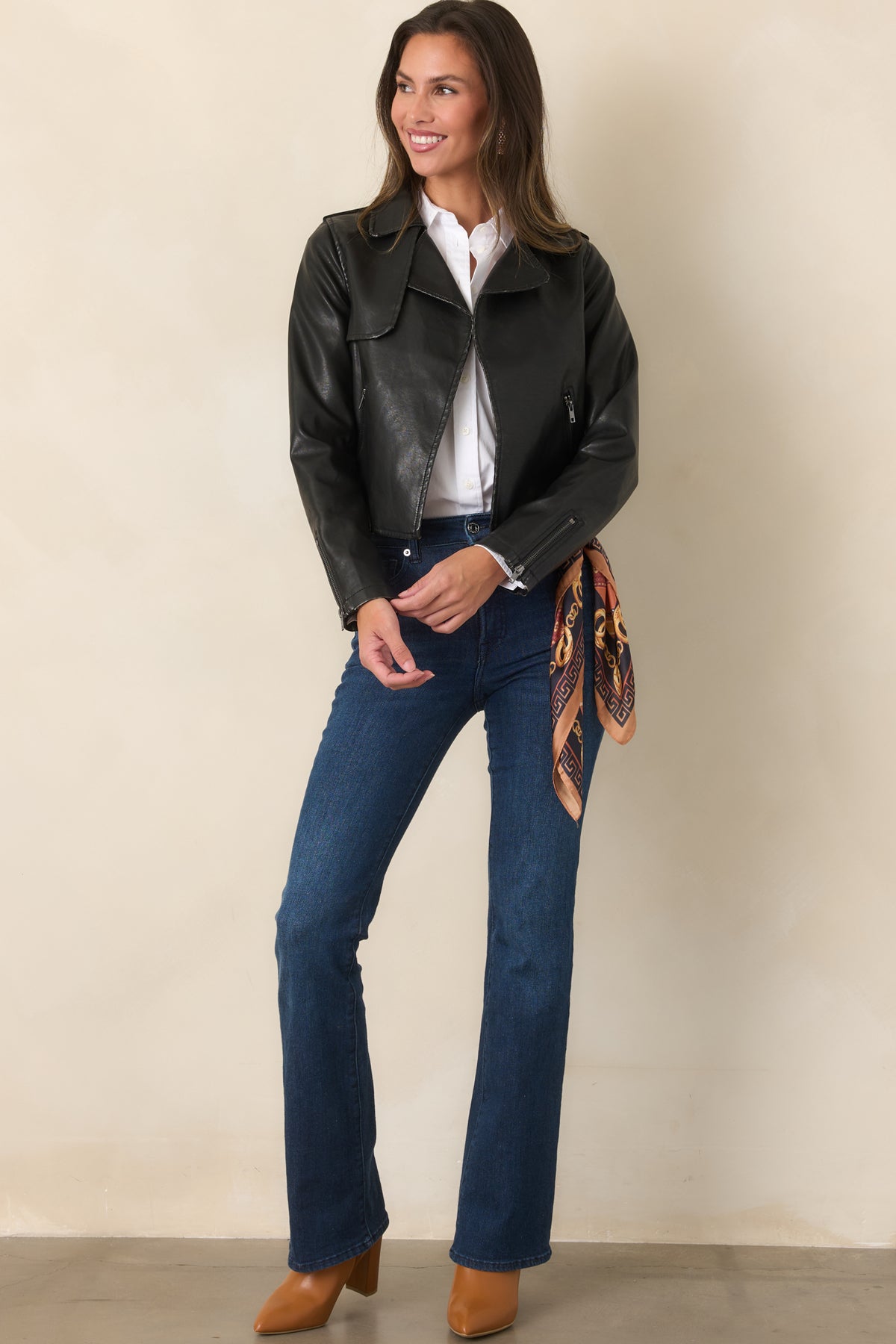 Cropped faux leather jacket in black with wide notched lapels, zippered side pockets, and zippered sleeve cuffs.