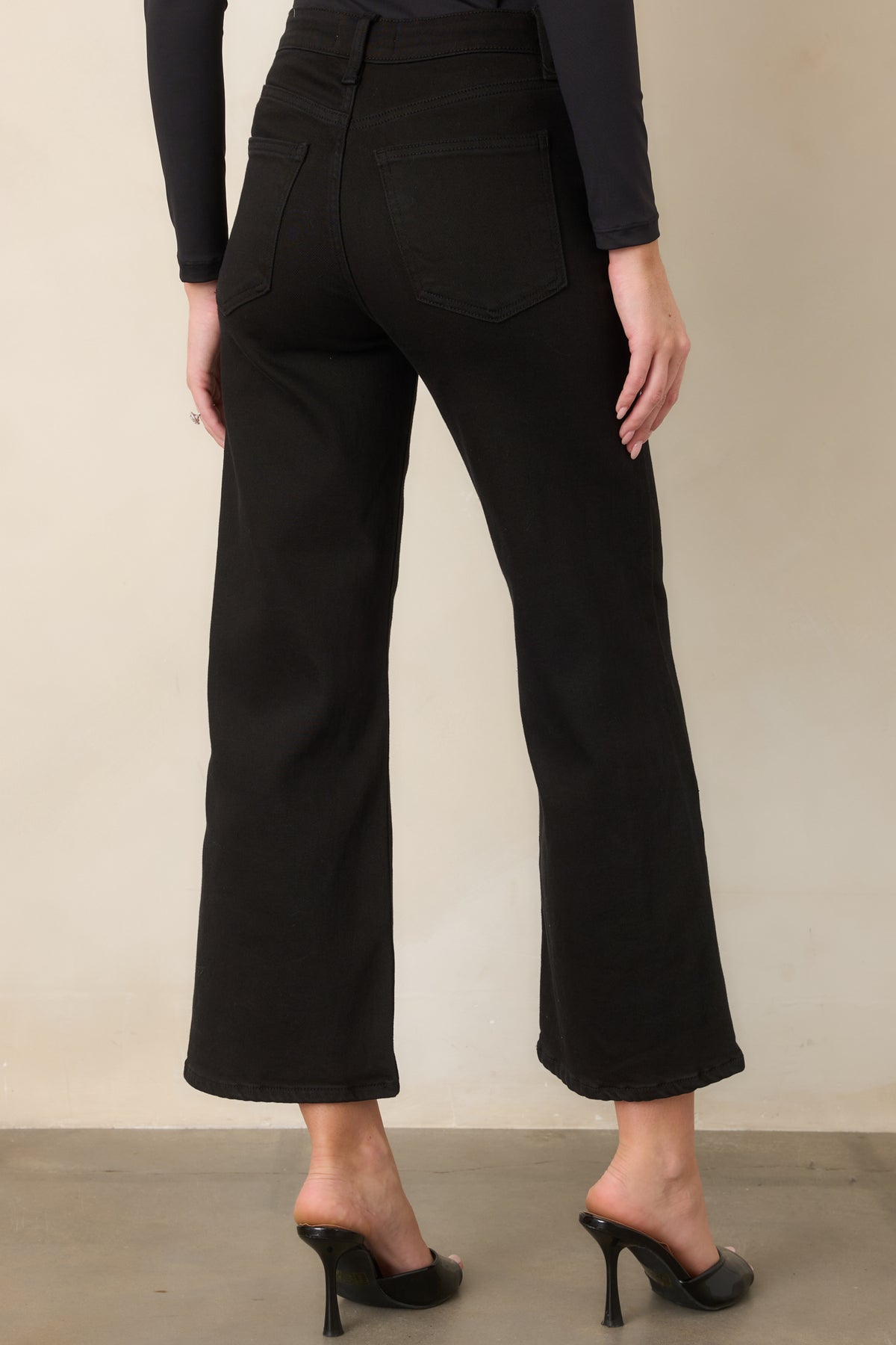 Rear of the black cropped jeans showing the high-rise waist, relaxed wide-leg silhouette, belt loops, and back pockets.