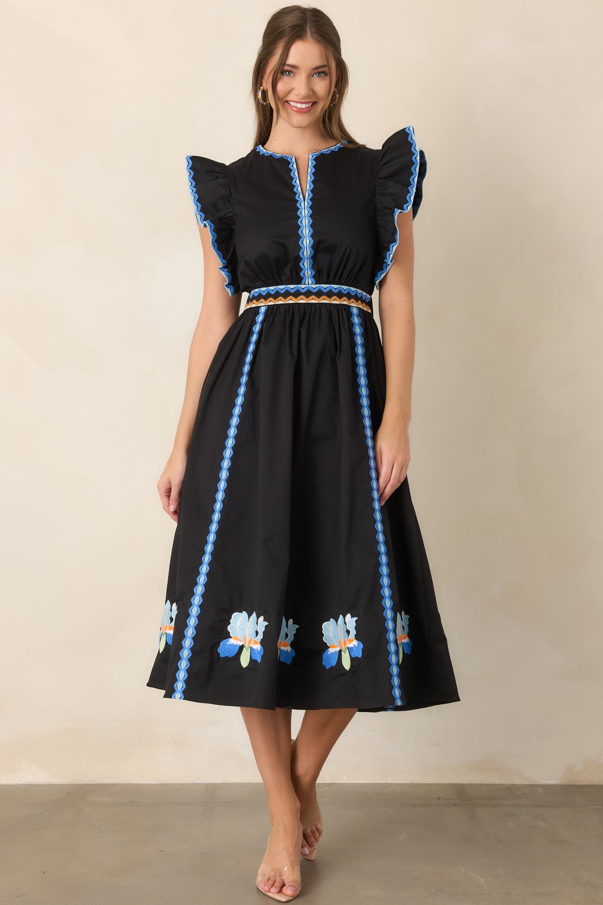 Black dress with vertical geometric embroidery extending along the A-line skirt.