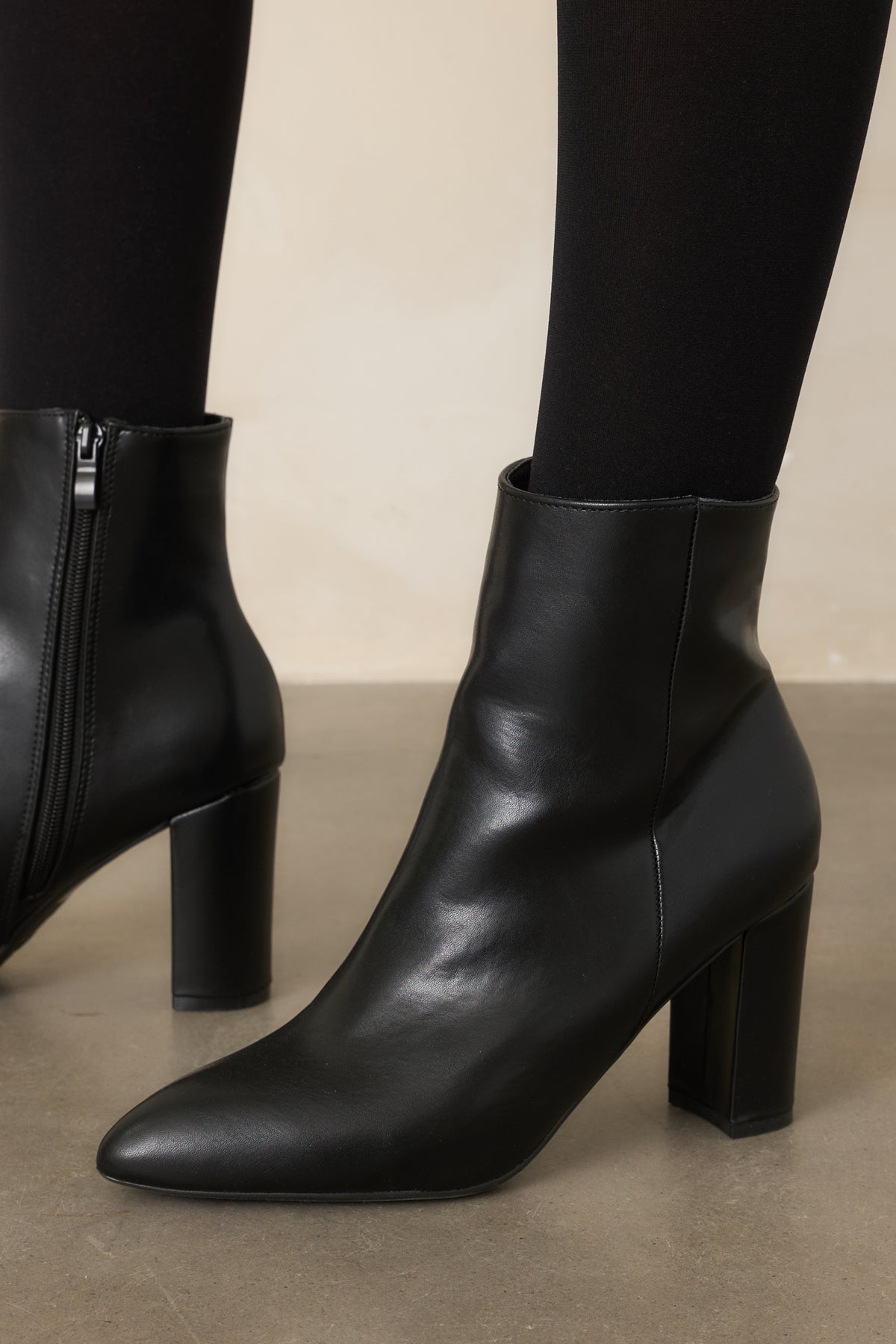 Black faux leather ankle boots featuring pointed toes, outer seam detailing, and block heels.