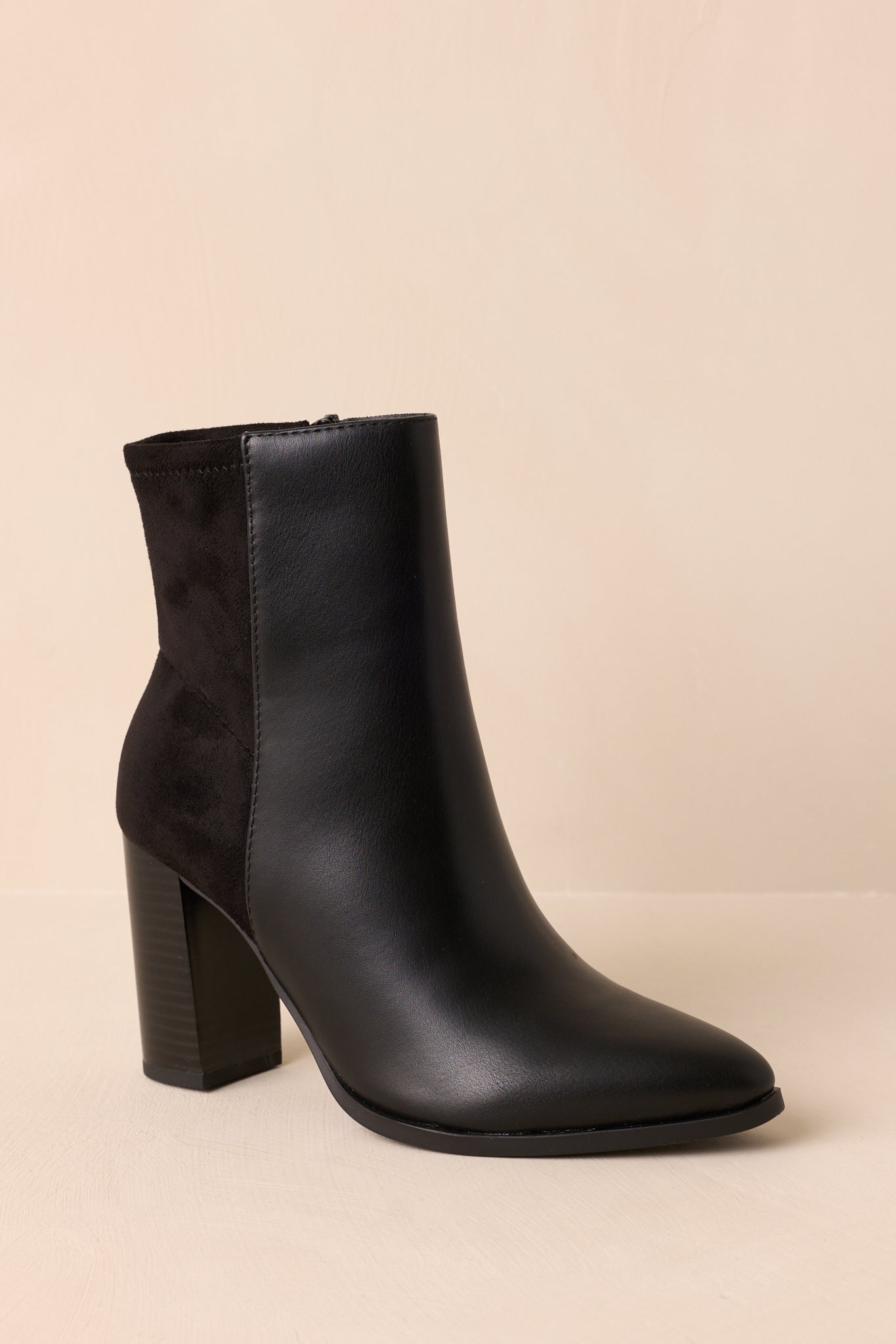 Black faux leather ankle boots showcasing a sleek silhouette, tonal faux suede panel, inner side zipper, and structured block heel.
