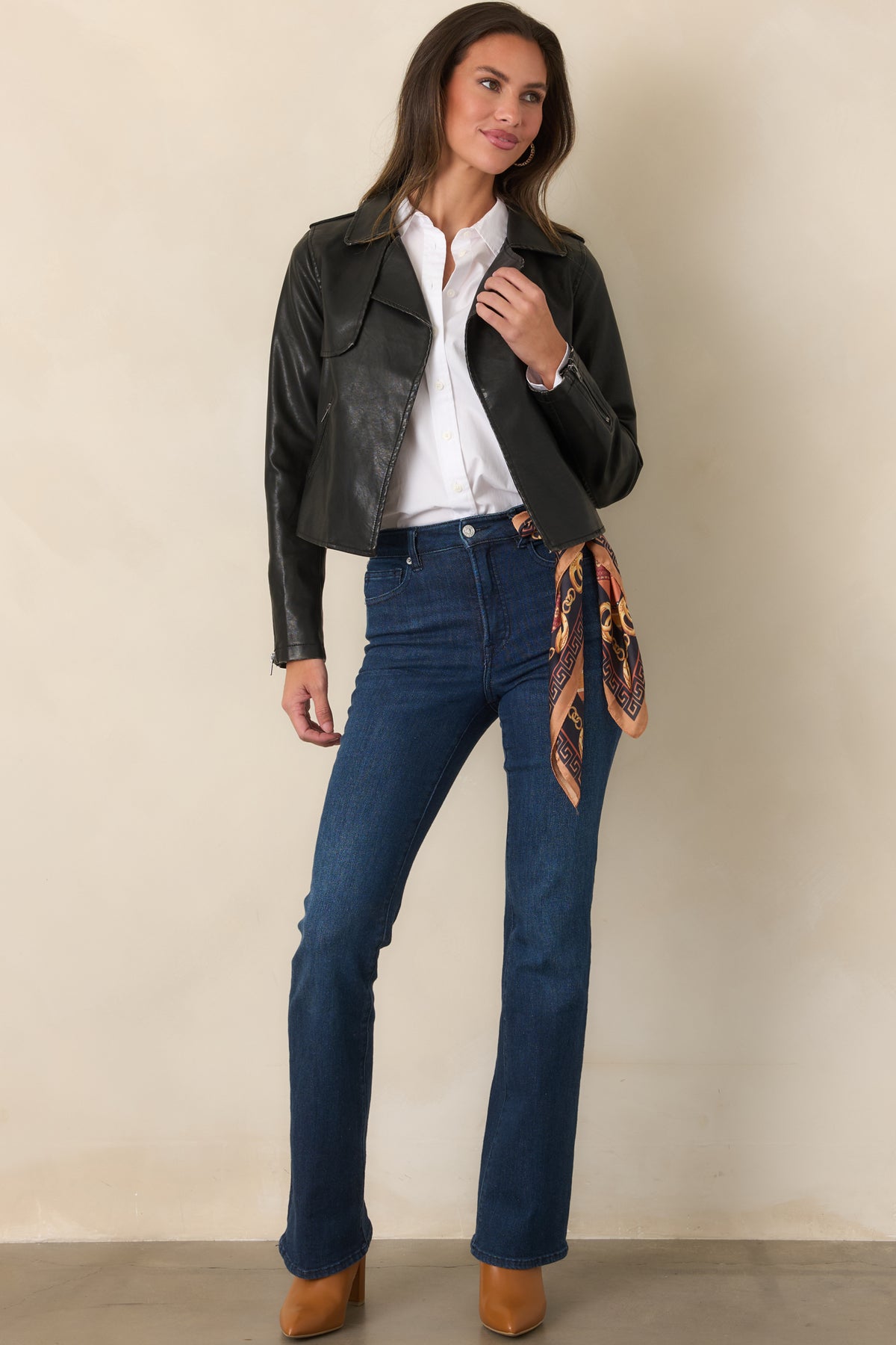Black faux leather jacket with a cropped fit, wide notched lapels, open front, and long sleeves with zippered cuffs.