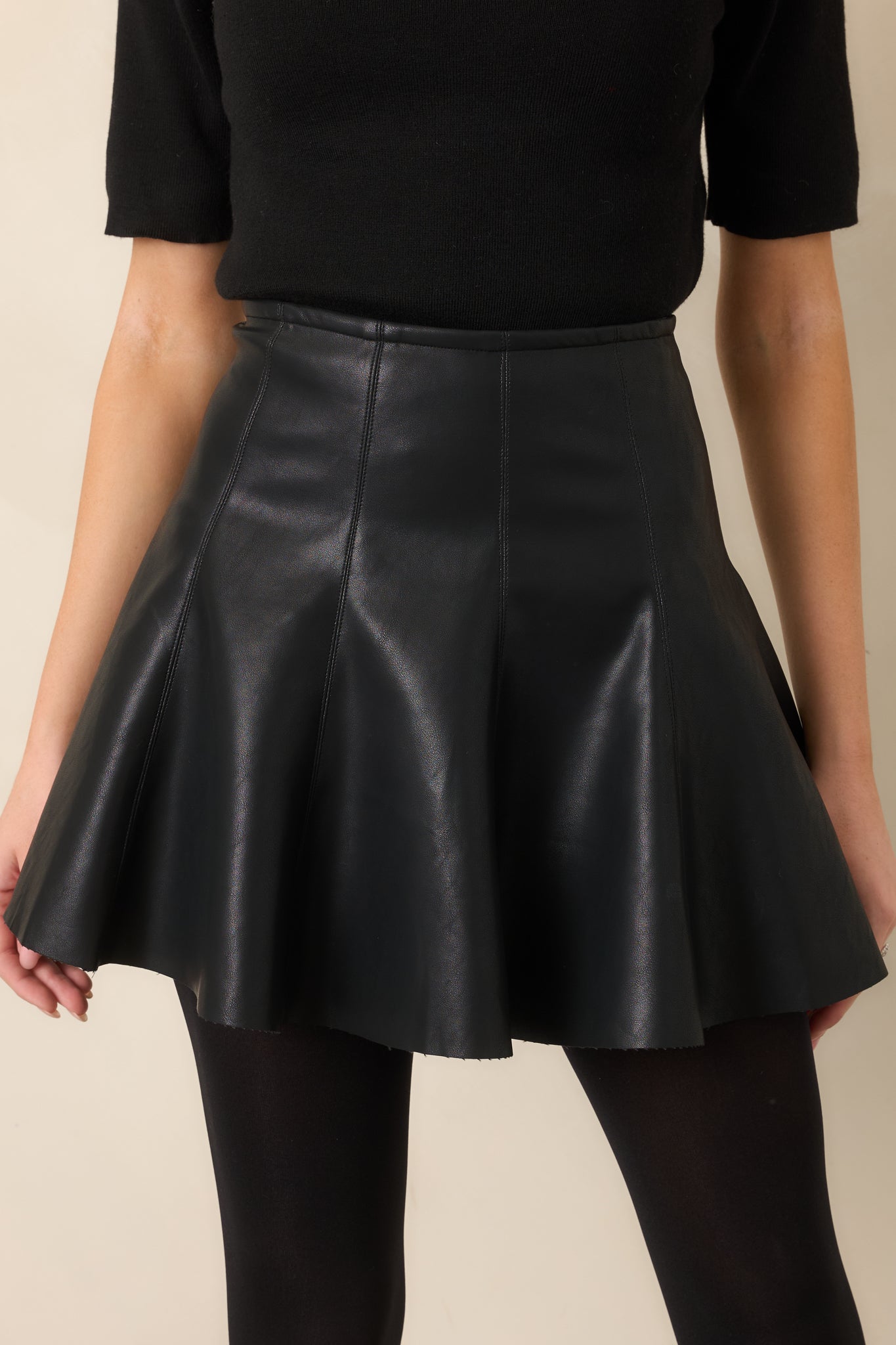 Close-up of the black faux leather surface and paneled seam detailing through the waist.