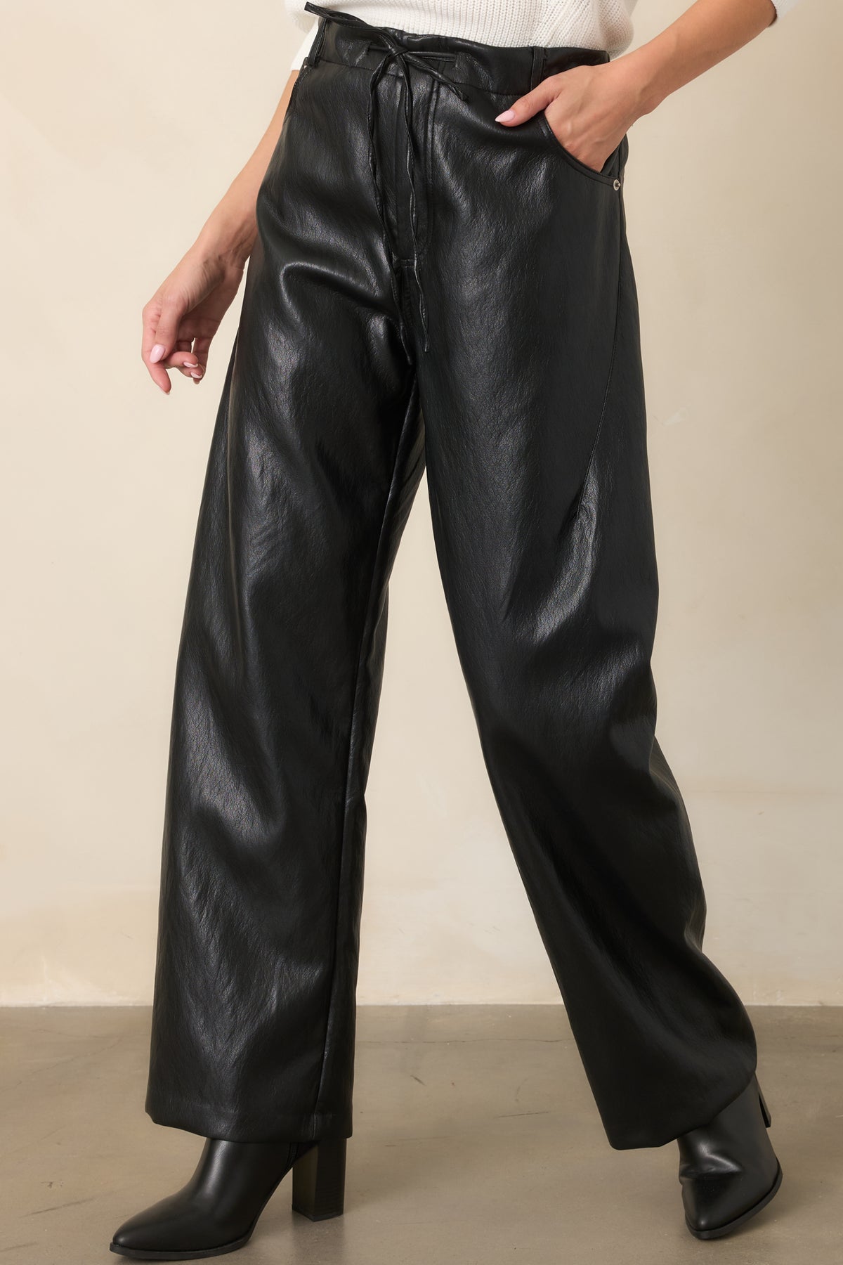 Black faux leather pants showcasing the elastic waistband and straight wide-leg construction.