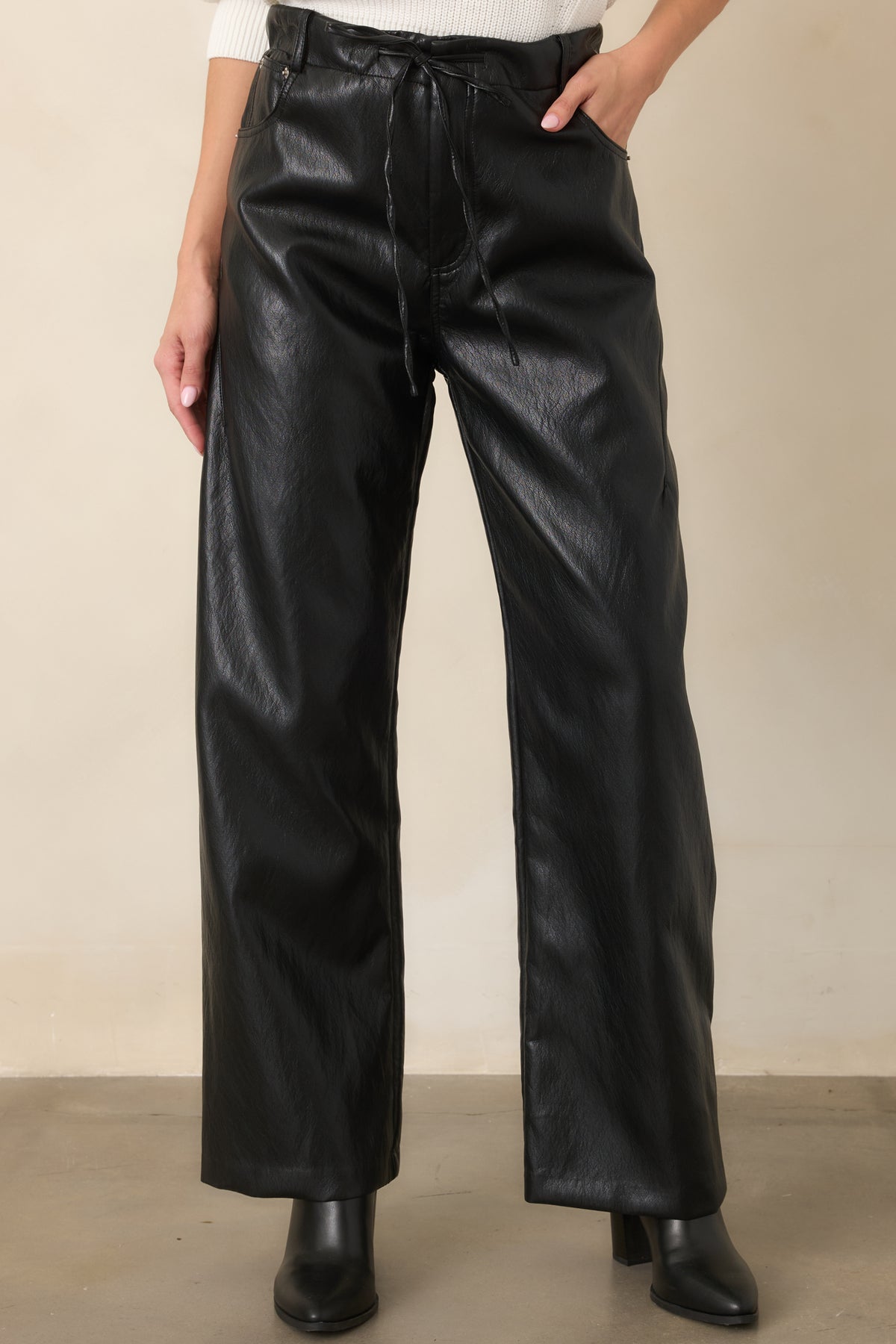 Black faux leather pants featuring functional side patch pockets and a clean wide-leg silhouette.
