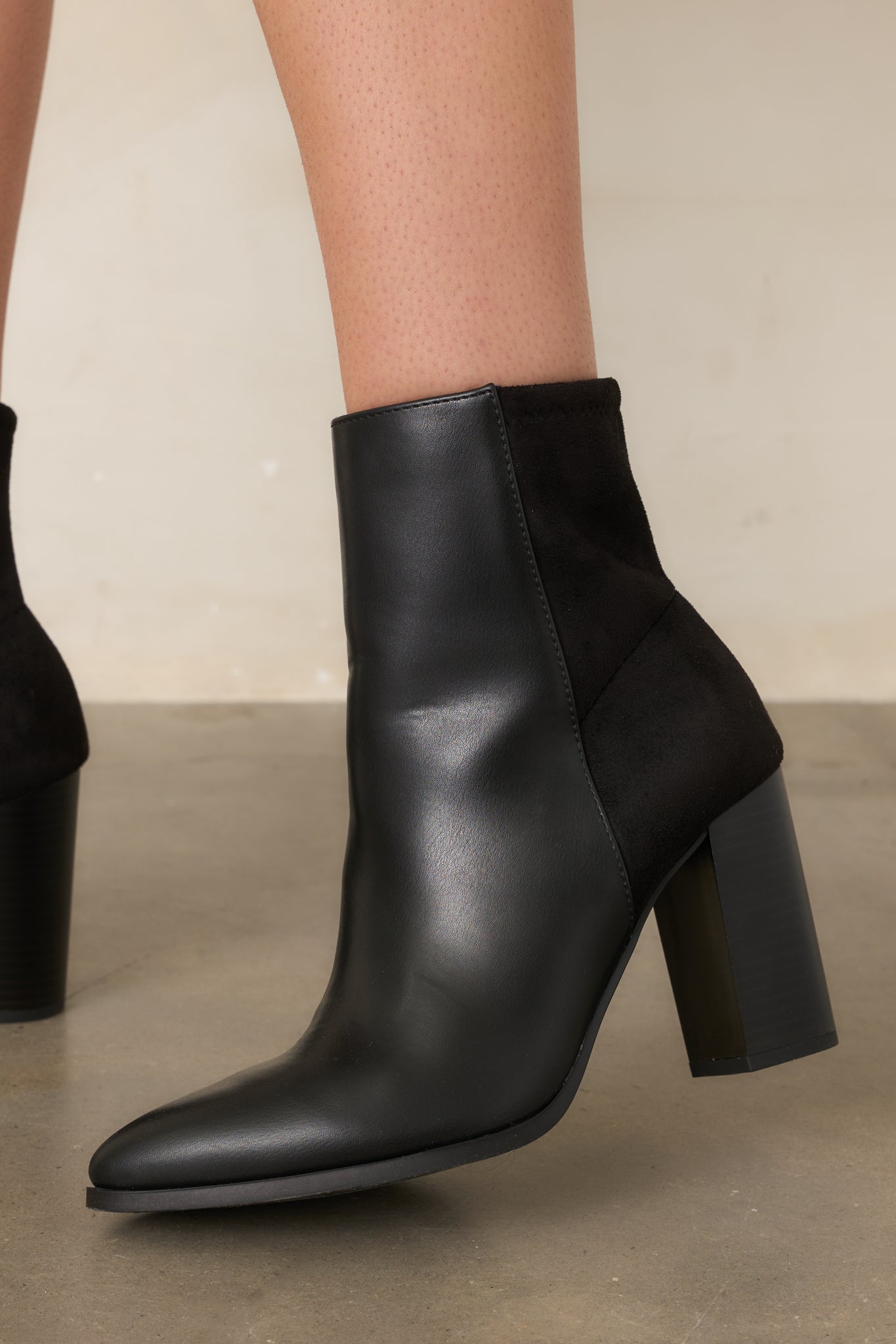 Close view of the black boots highlighting the pointed toe, smooth faux leather finish, and sleek front construction.