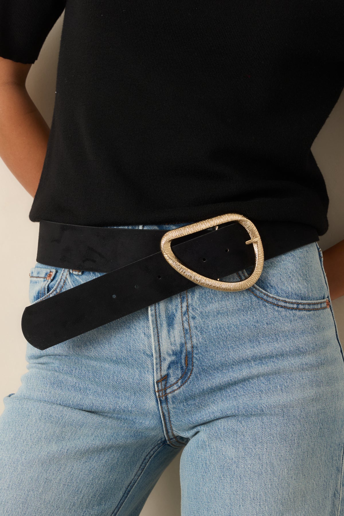 Wide black faux suede belt with an oversized textured gold-tone asymmetrical curved buckle.